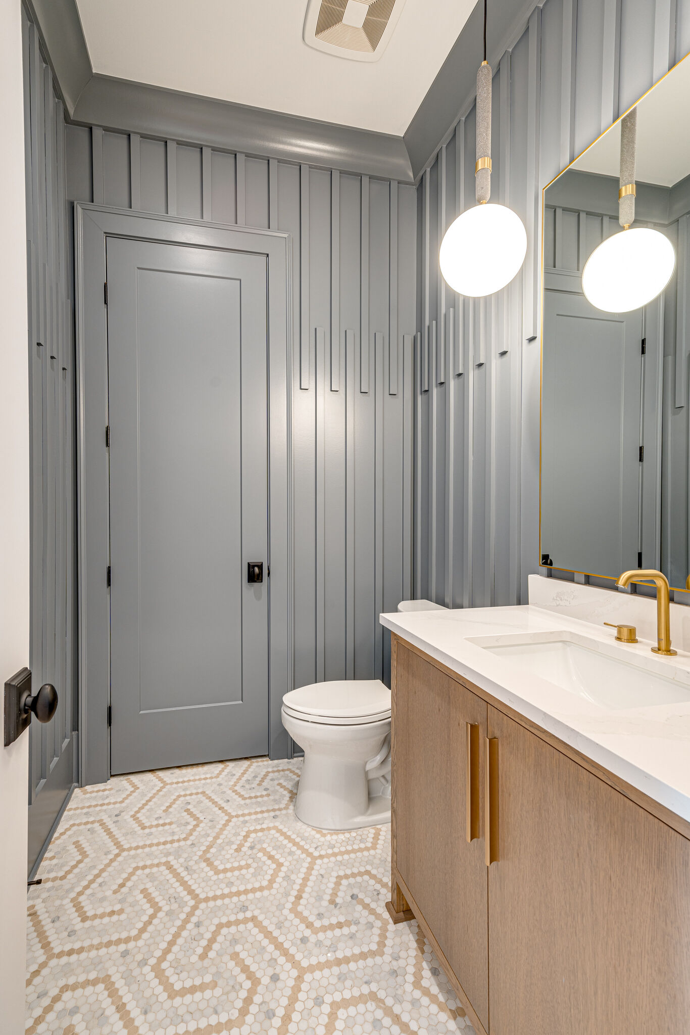 Geometric tiled floor with deep blue painted walls with trim work and hanging circular sconces