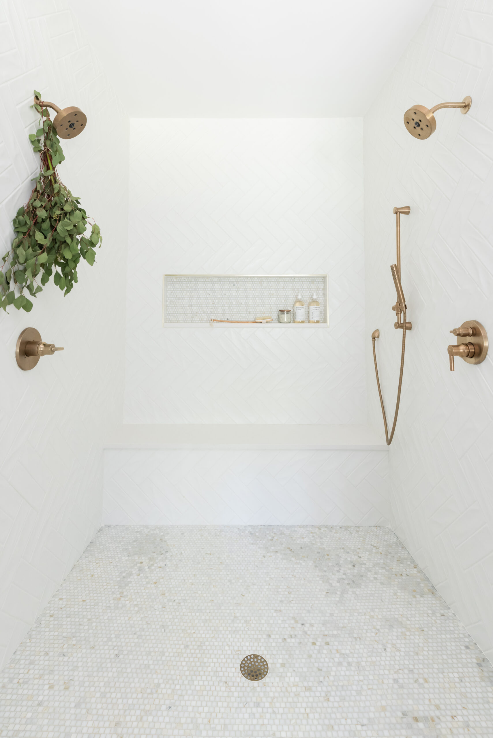 Walk-in shower with gold shower head and built-in rectangular niche