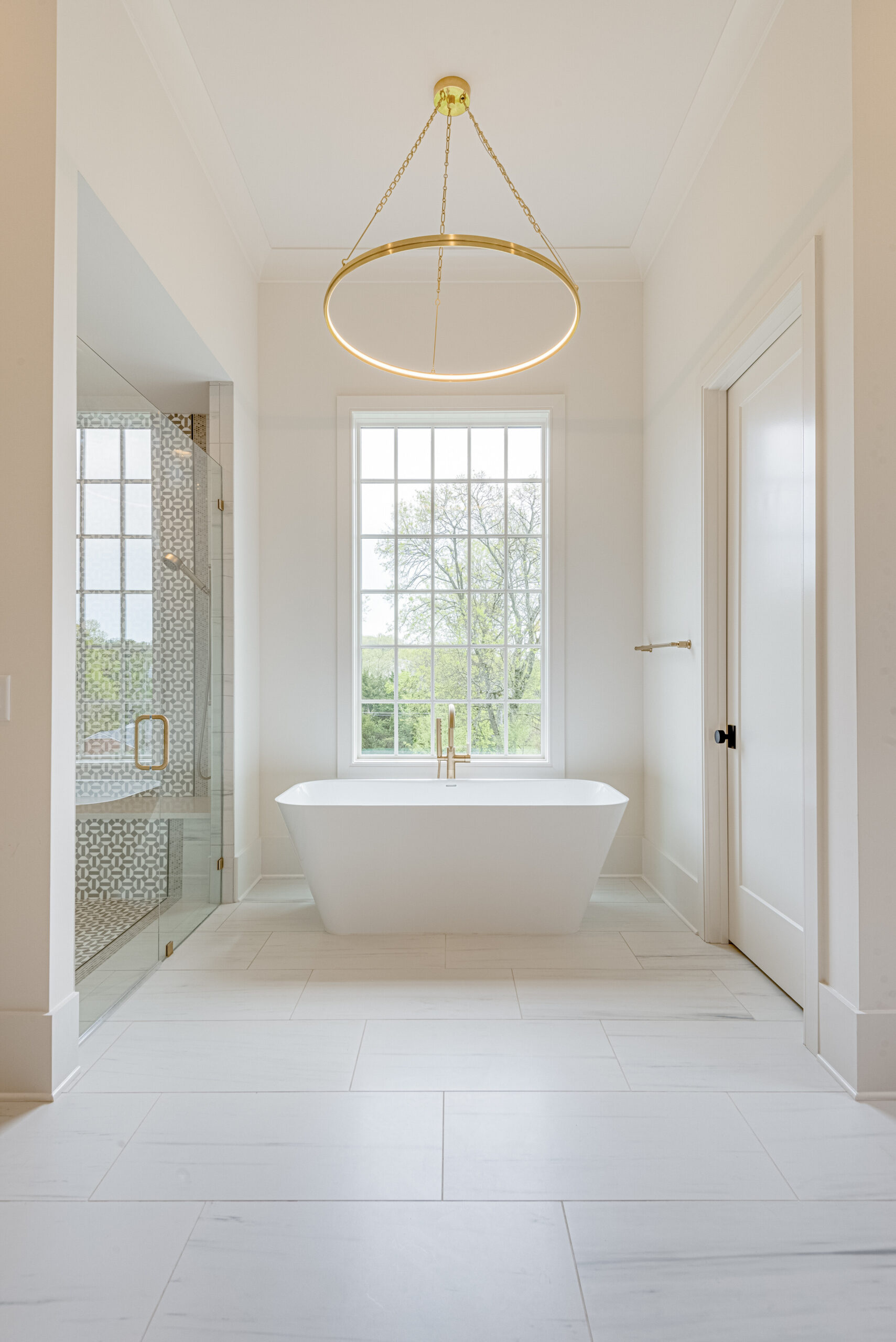 Master bath with freestanding tub under large paneled window and a marble glass walk-in shower