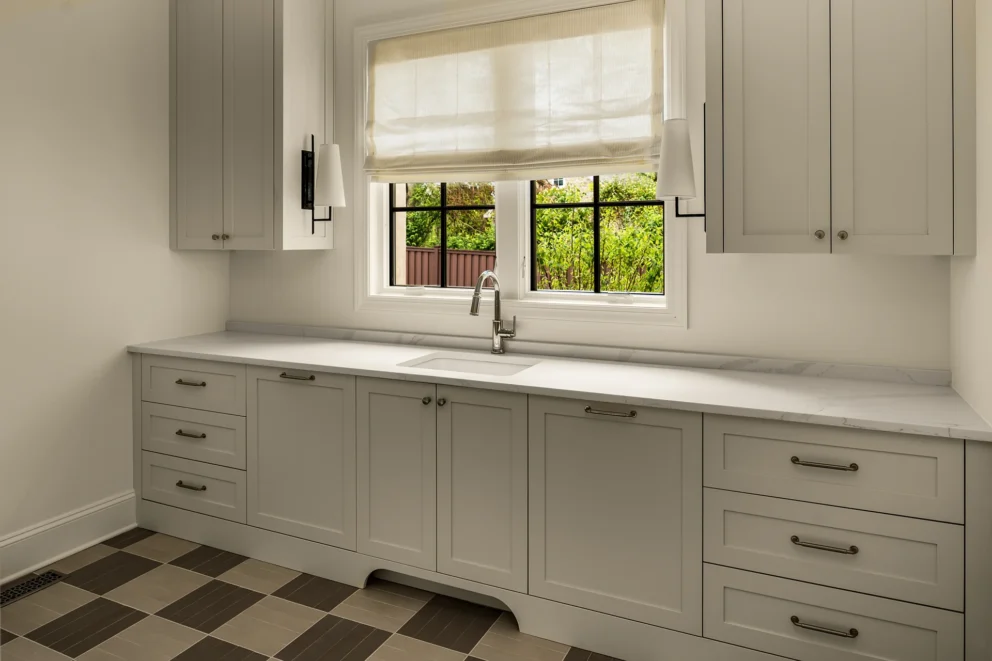 Utility room with light gray cabinets, marble counter, window, and checkerboard tile floor
