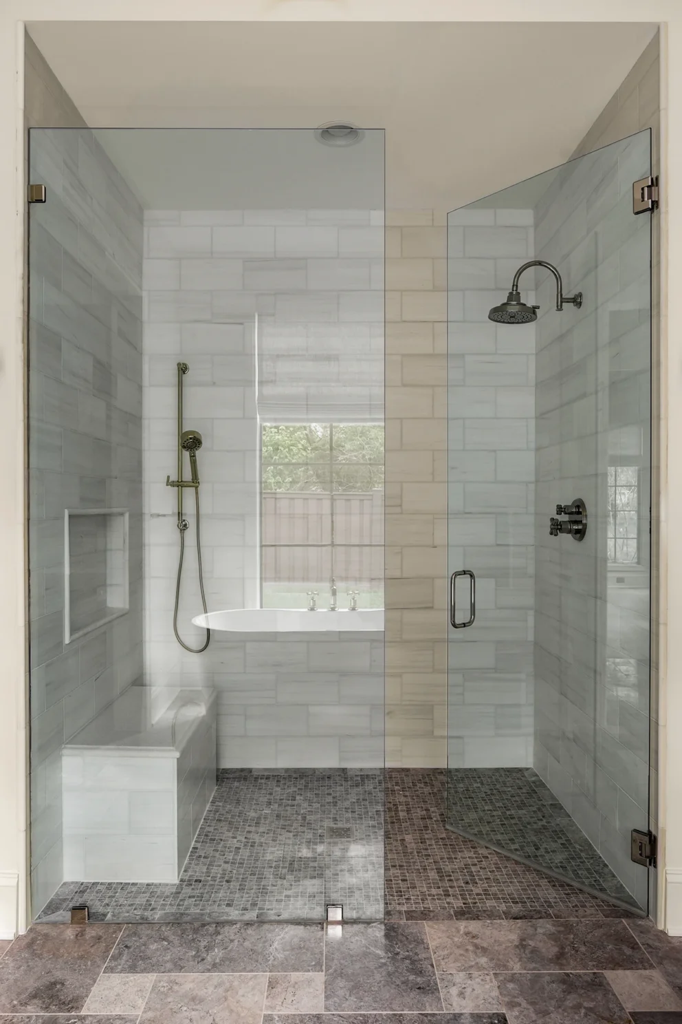 Walk-in shower with marble tile, frameless glass enclosure, built-in bench, and pebble stone floor