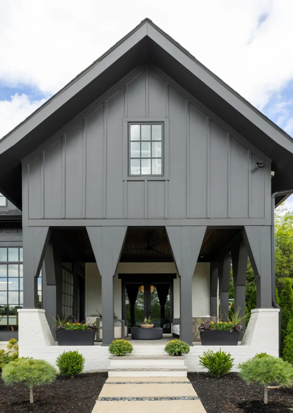 Dark gray board-and-batten home exterior with a tall gable and covered porch with columns