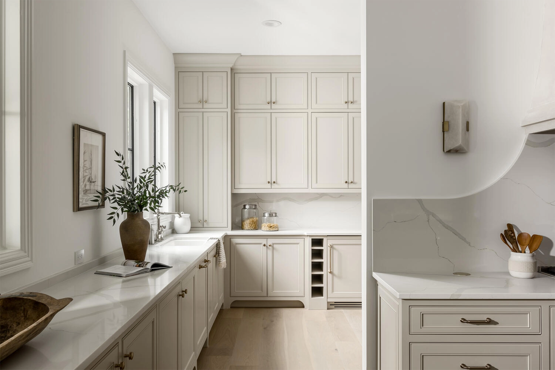 Butler's pantry with cream cabinetry, marble countertops, and a vase of greenery
