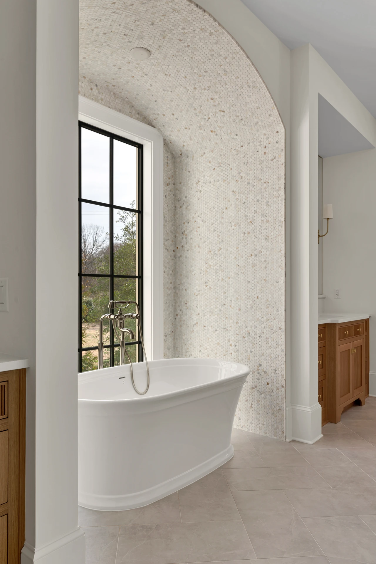 Master bath with arched textured-wallpaper niche and a freestanding tub under a black-grid window