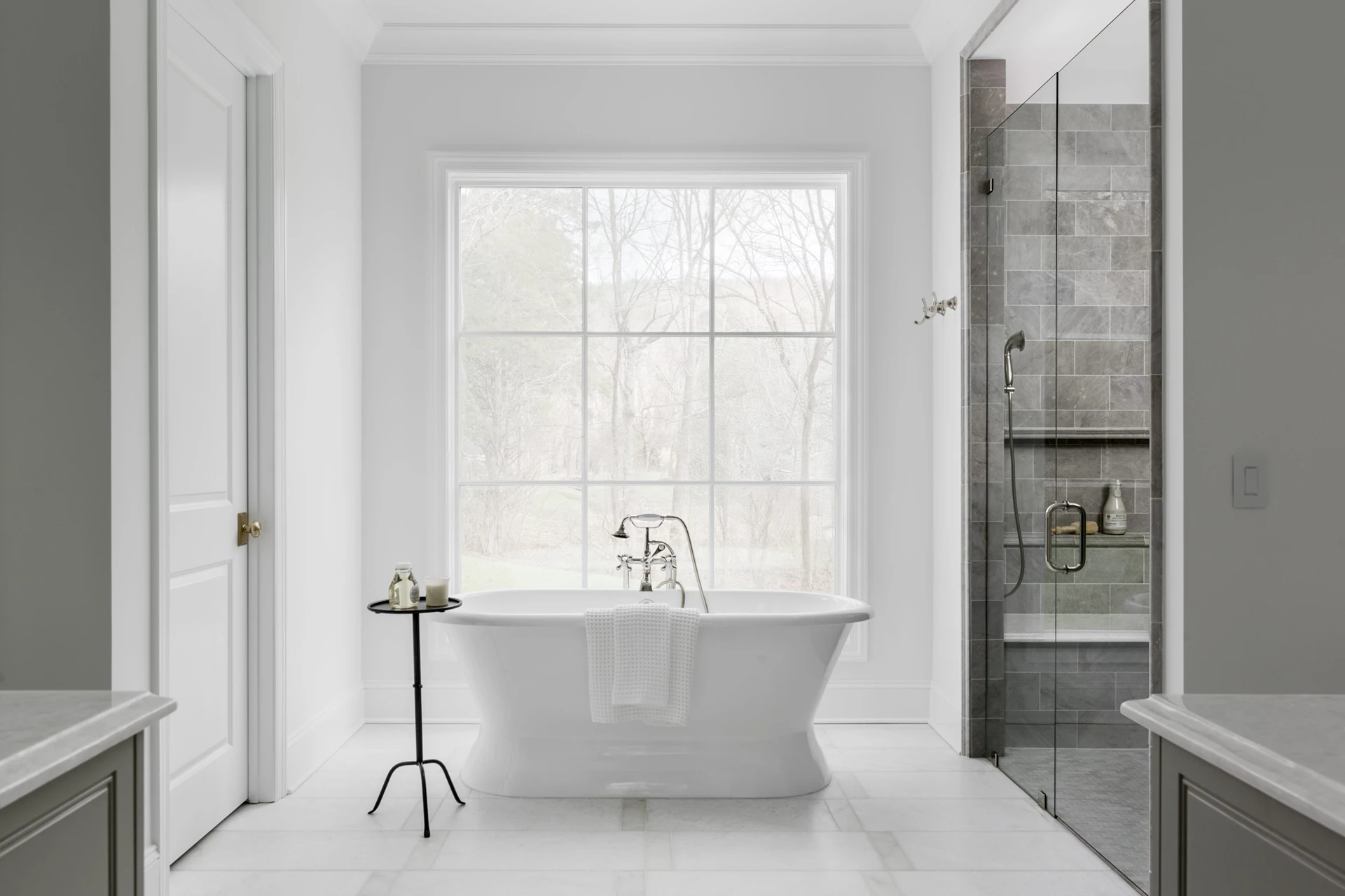 Master bath with freestanding tub under a large window and a gray-tile glass walk-in shower
