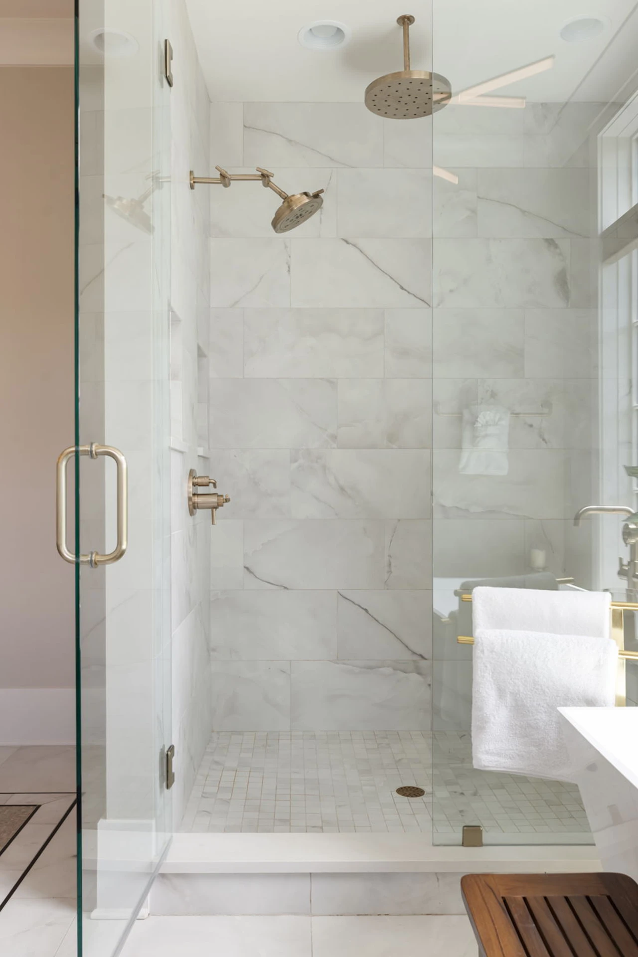 Marble glass walk-in shower with dual shower heads, brass fixtures, and a towel bar
