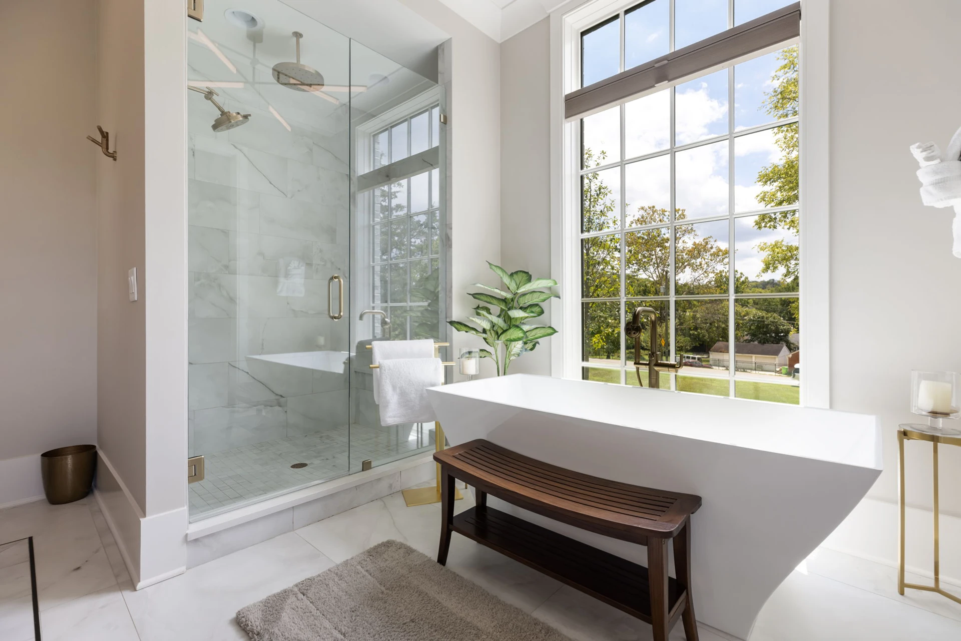 Master bath with marble glass walk-in shower, freestanding tub, wood bench, and a large picture window