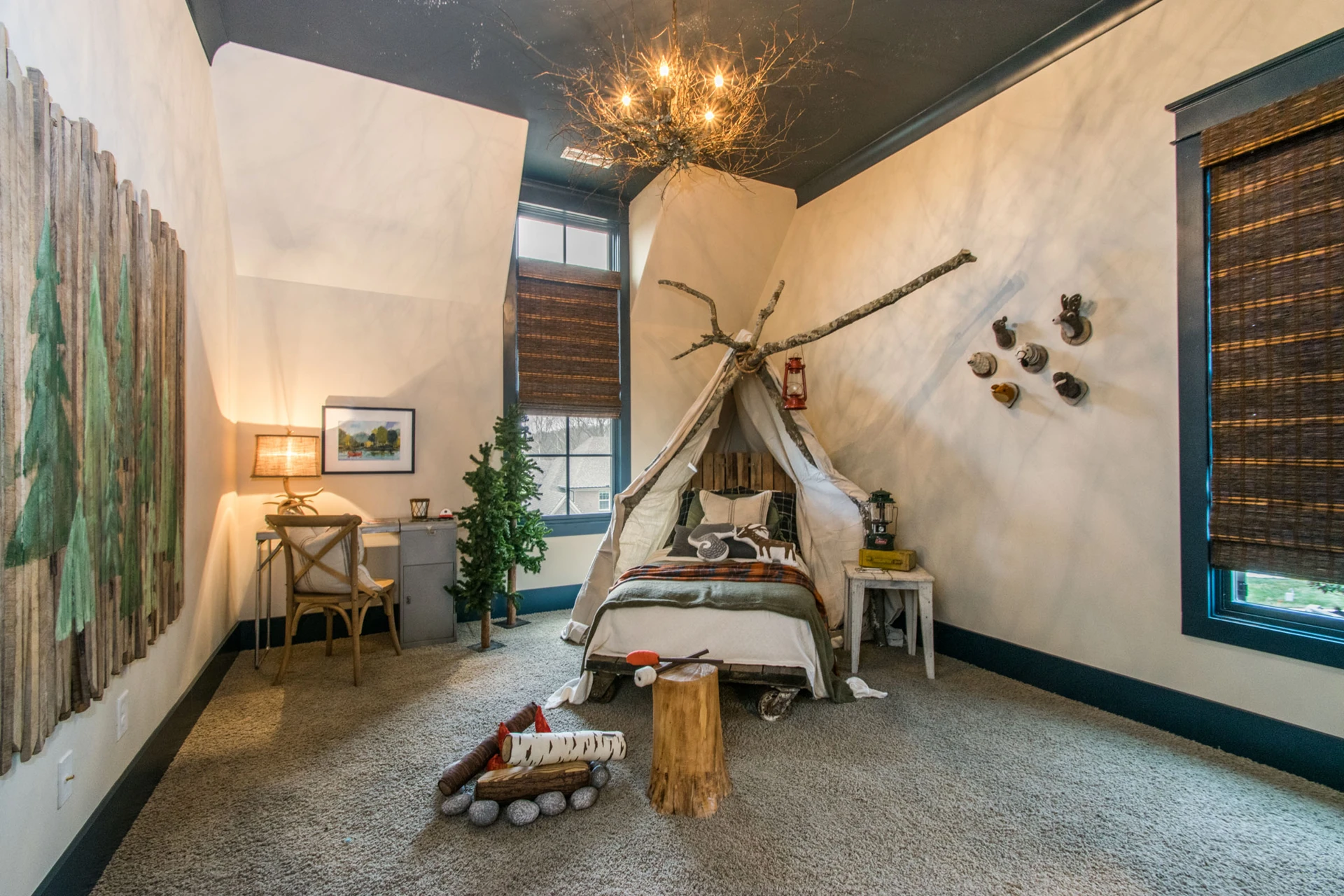 Kids' camping-themed bedroom with a teepee tent over the bed, twig chandelier, and tree wall art