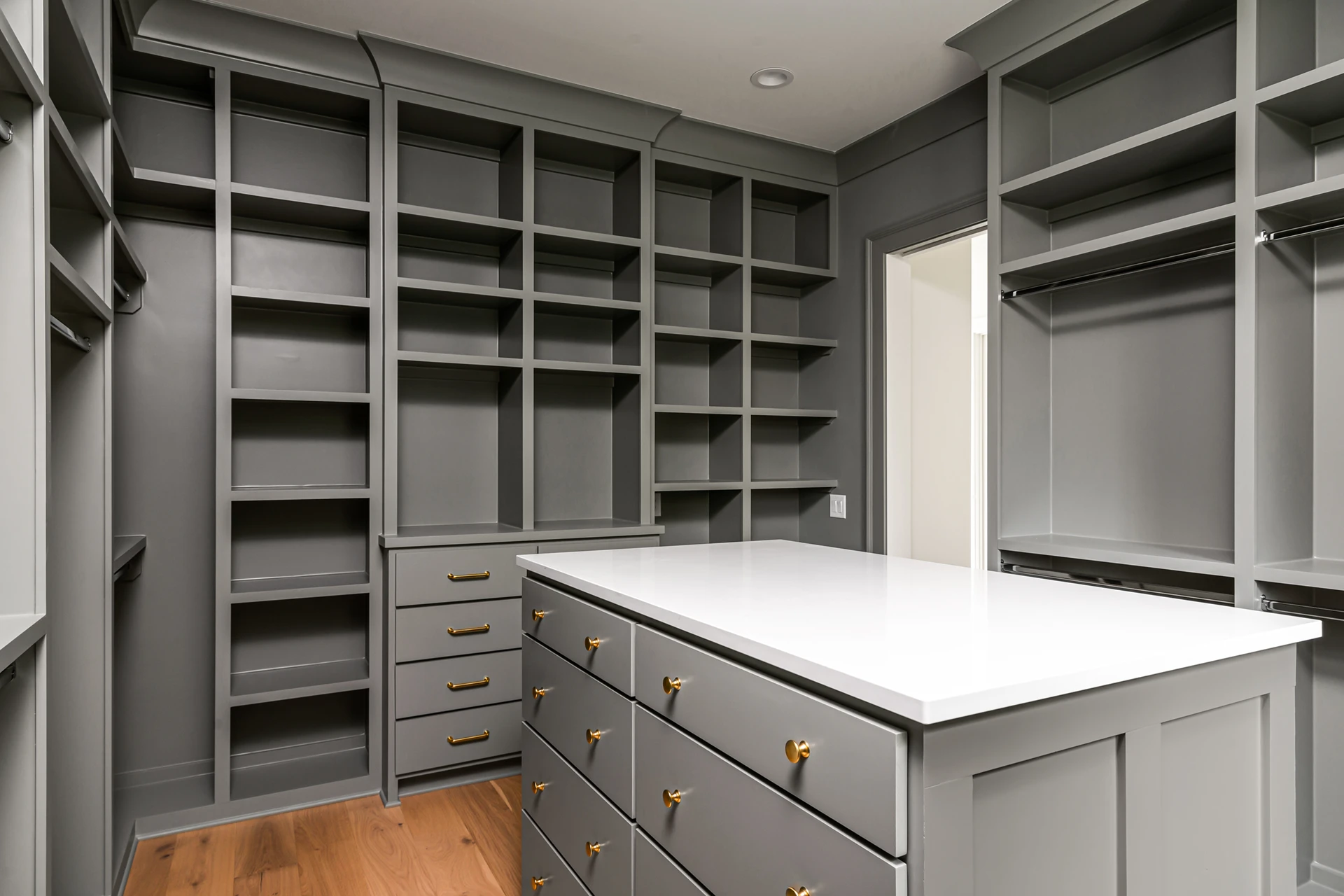 Large gray walk-in closet with open shelving, hanging rods, and a center island with white top