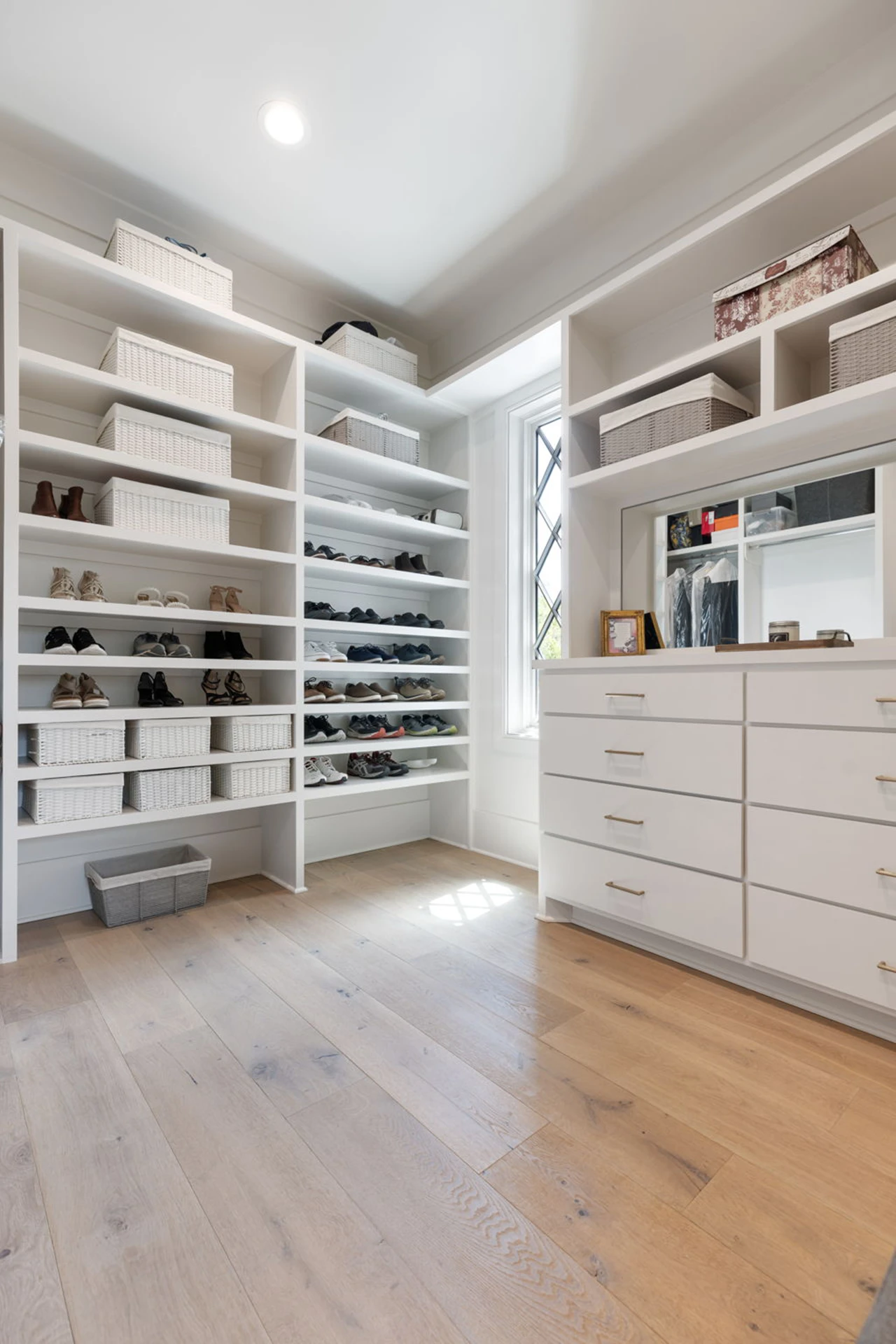 White walk-in closet with shoe shelving, drawers, and a mirror