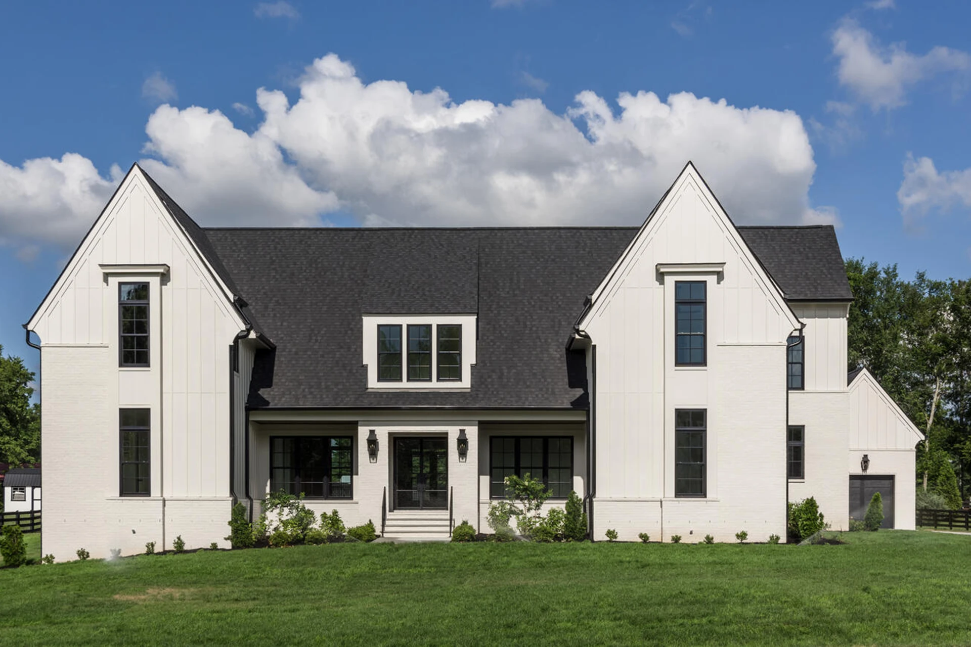 White two-story home with dark roof, twin steep gables, and a symmetrical black-grid window facade