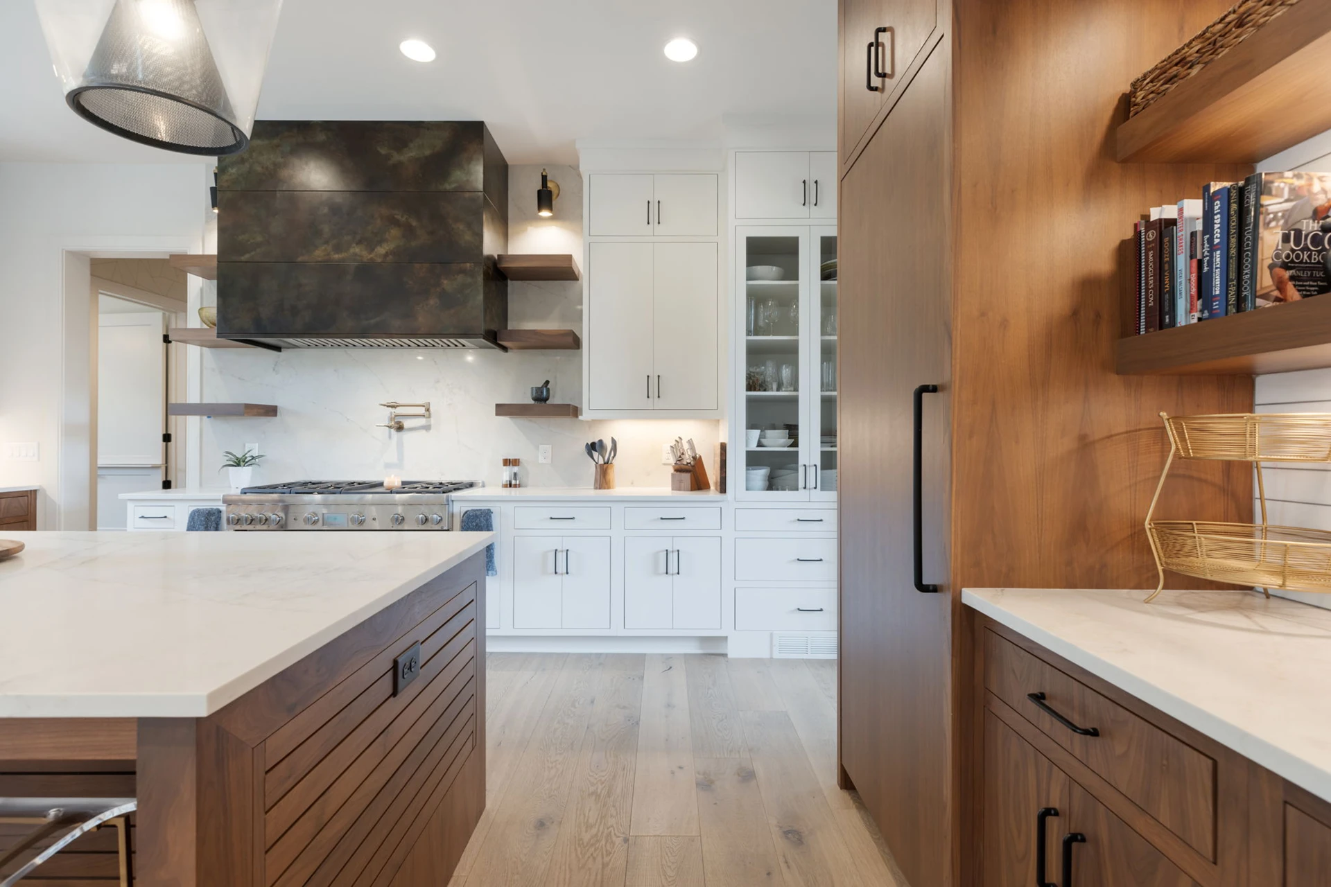 Kitchen with dark metallic range hood, white cabinets, wood island and pantry, and open shelving