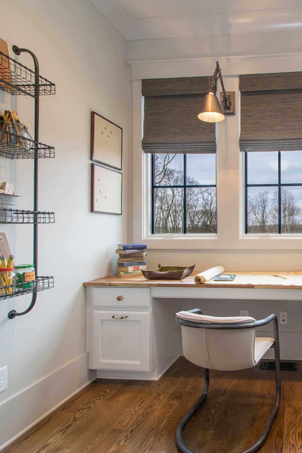 Desk nook with butcher-block desk, Roman shades, wire wall organizer, and a pendant light