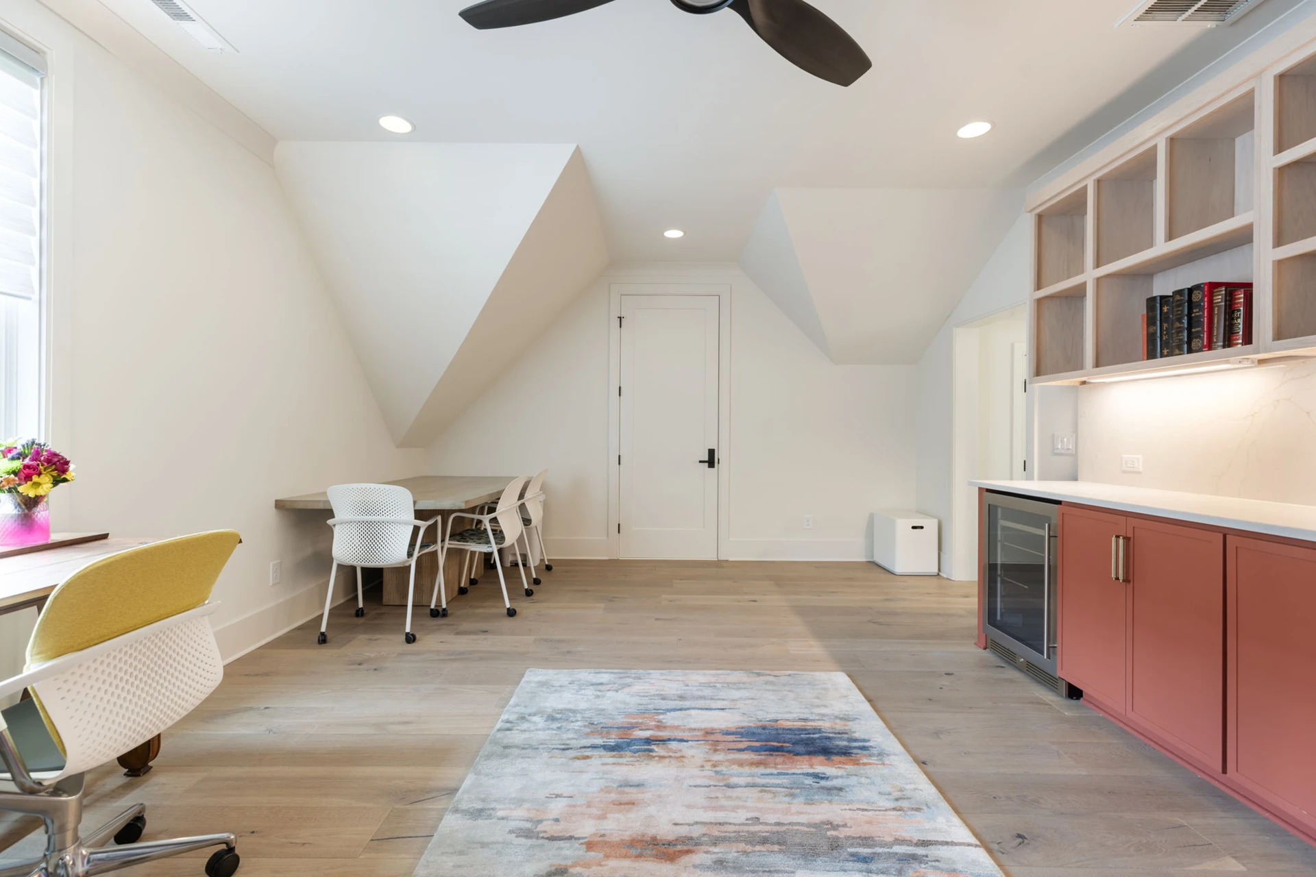 Loft bonus room with sloped ceiling, ceiling fan, desk, and terracotta cabinets with beverage fridge