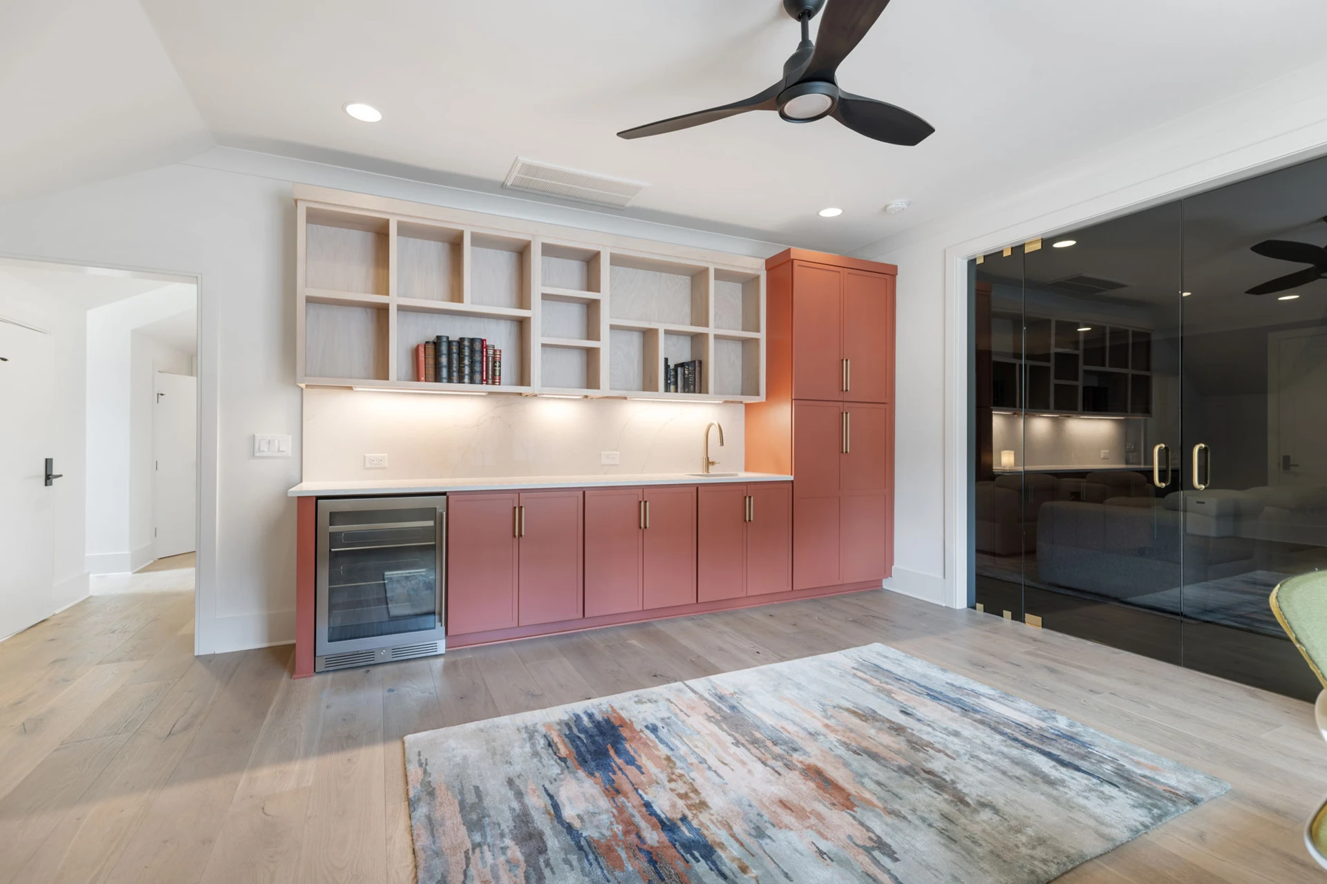 Bonus room bar with terracotta cabinets, open shelving, beverage fridge, and a black ceiling fan