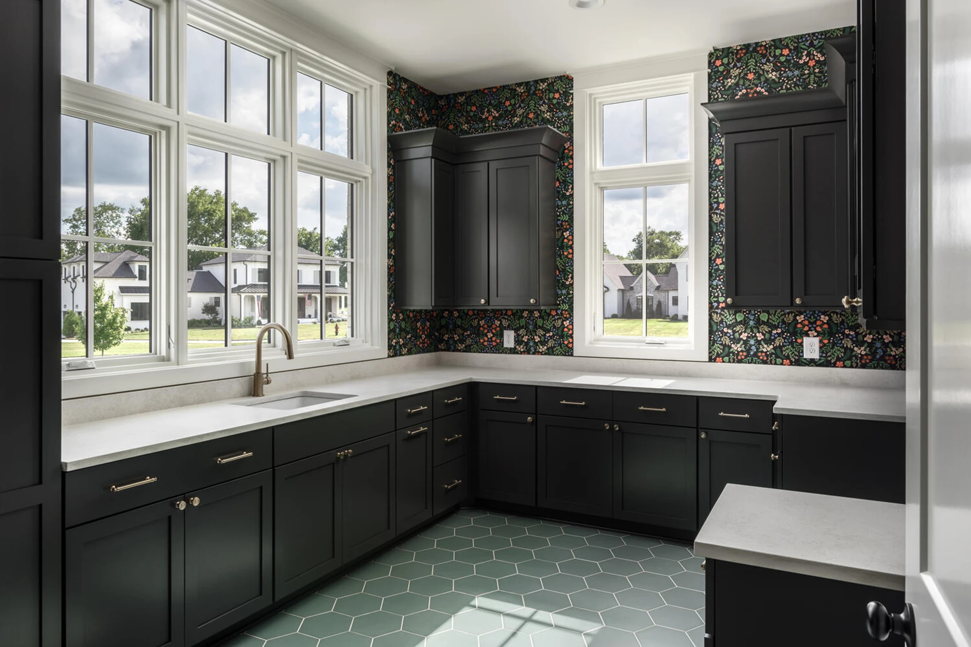 Kitchen with black cabinets, floral wallpaper, large windows, and a green hexagon tile floor