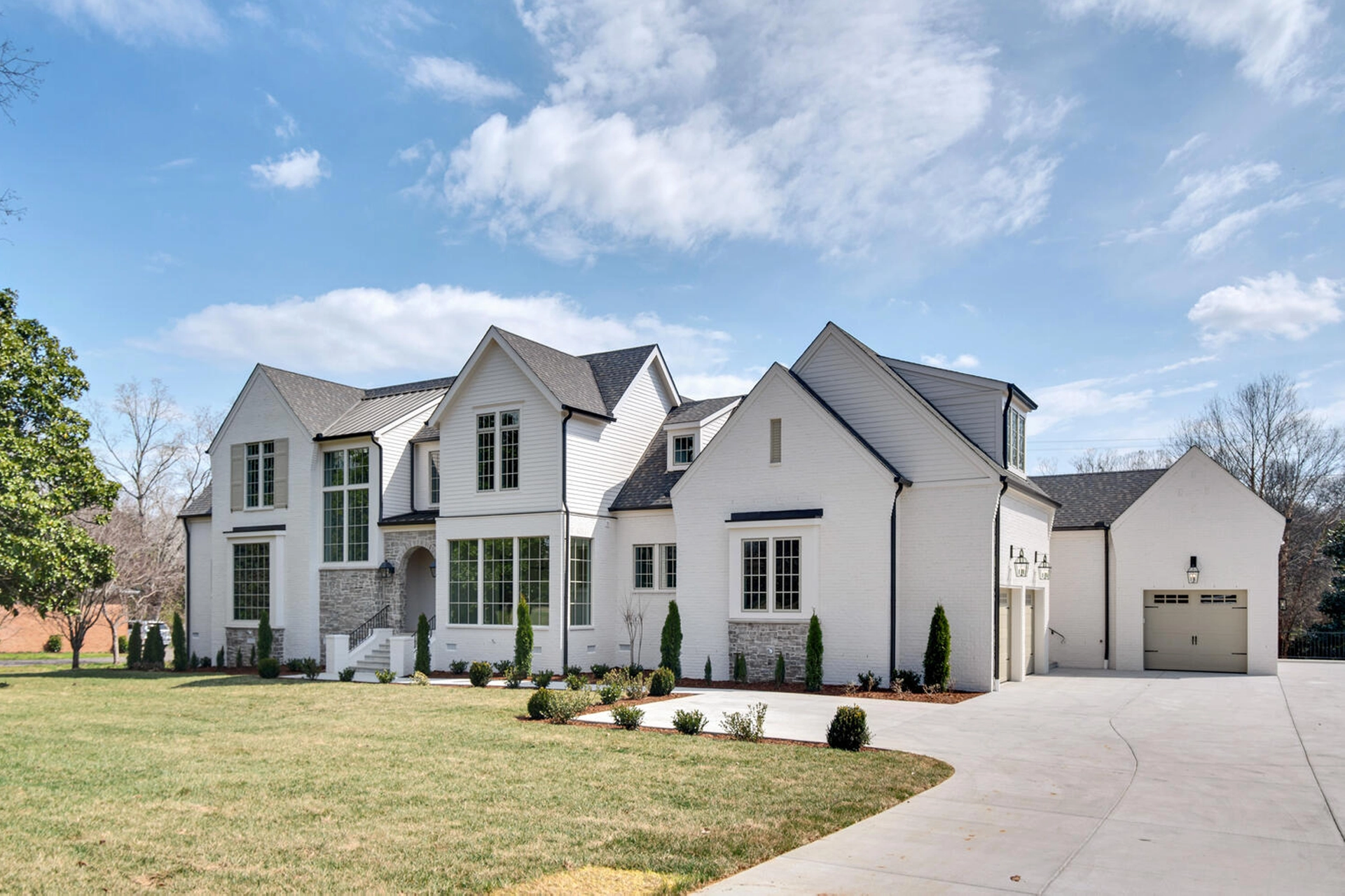 White two-story modern farmhouse exterior with attached garage under a blue sky