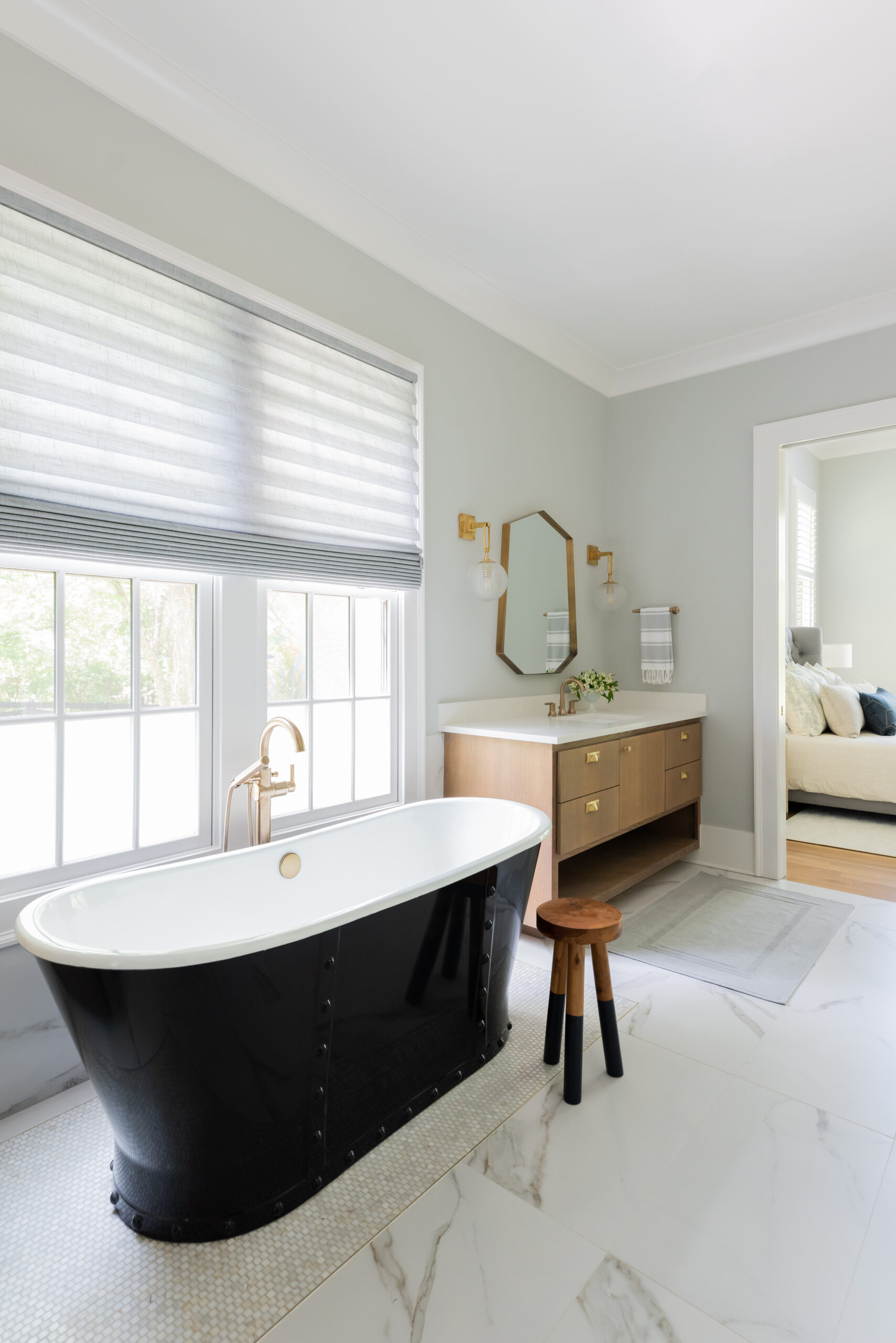 Corridor view of bathroom with dual light wood floating vanity and dark metal tub