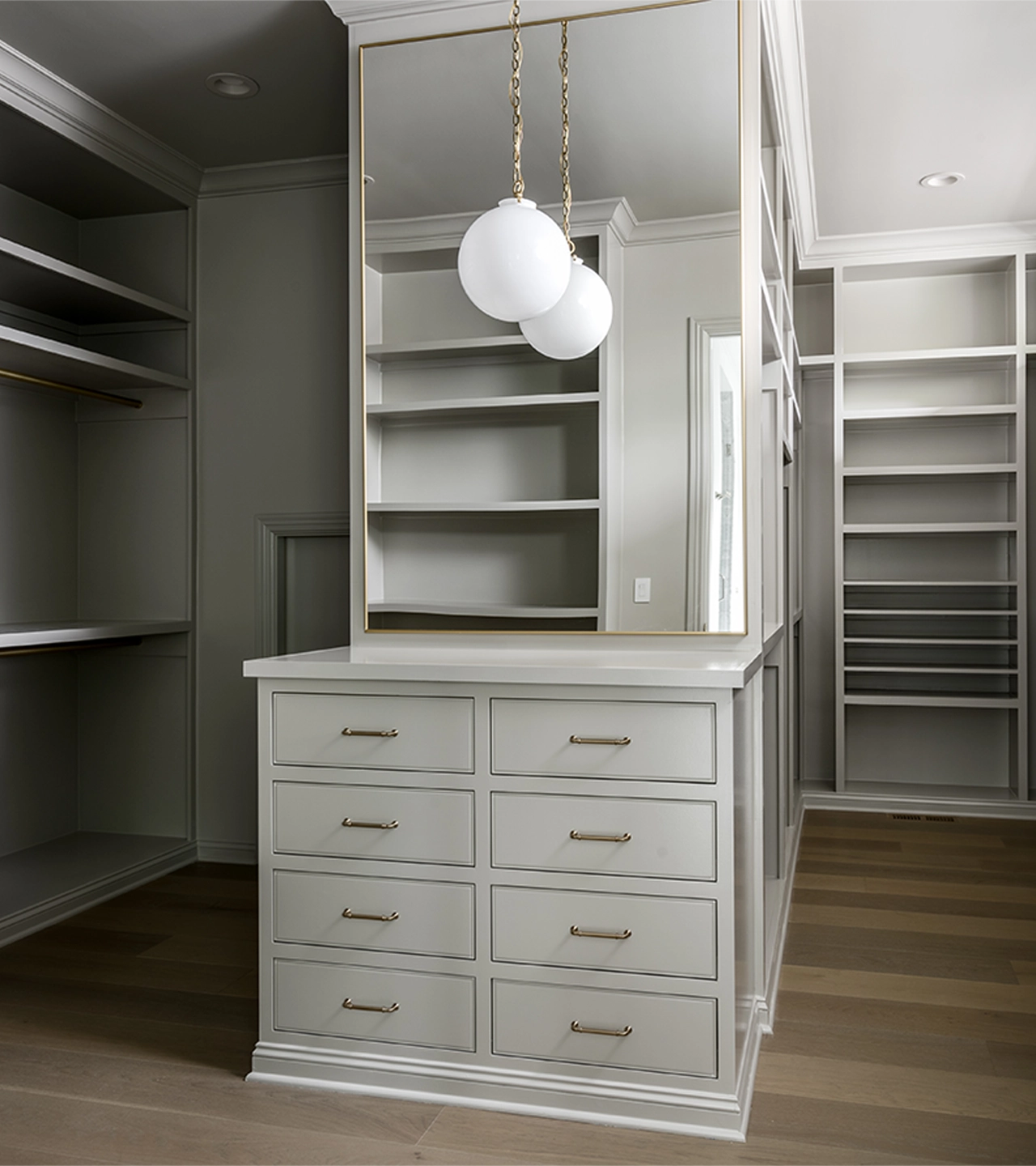 Large gray walk-in closet with open shelving, and a center island with a mirror and light