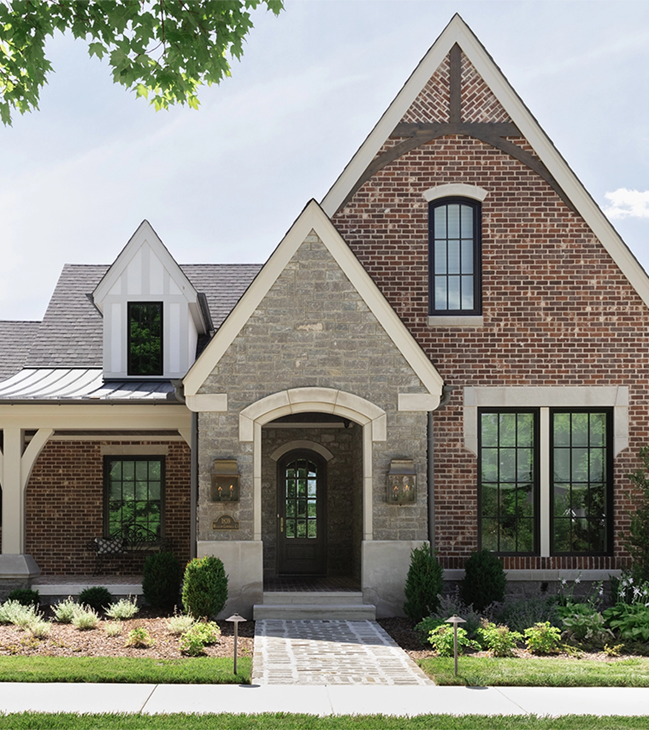 Front view of brick house with steep roof lines and a stone pathway to the front door