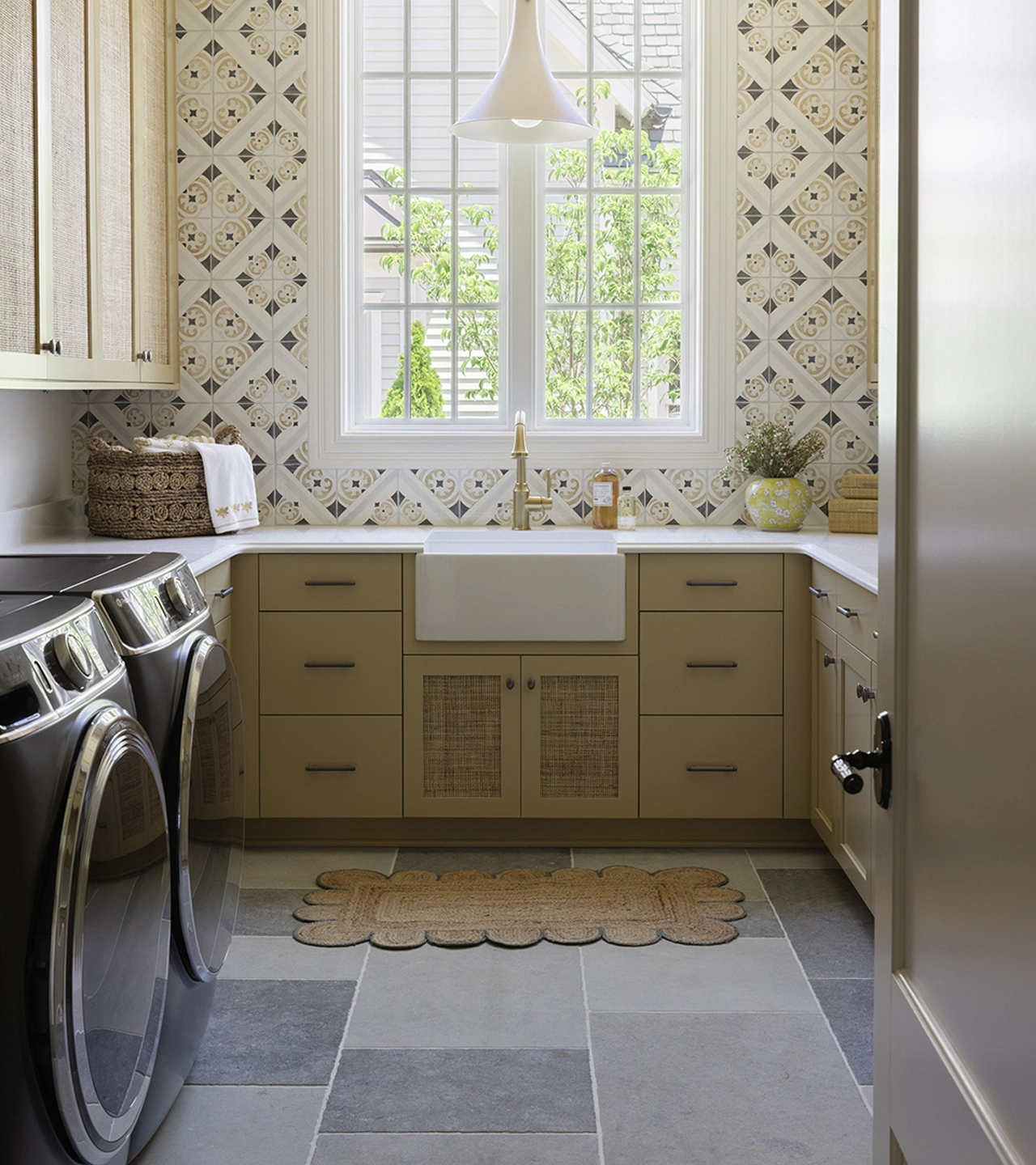 Laundry room with cabinets, black washer and dryer, patterned tile backsplash, and a two windows