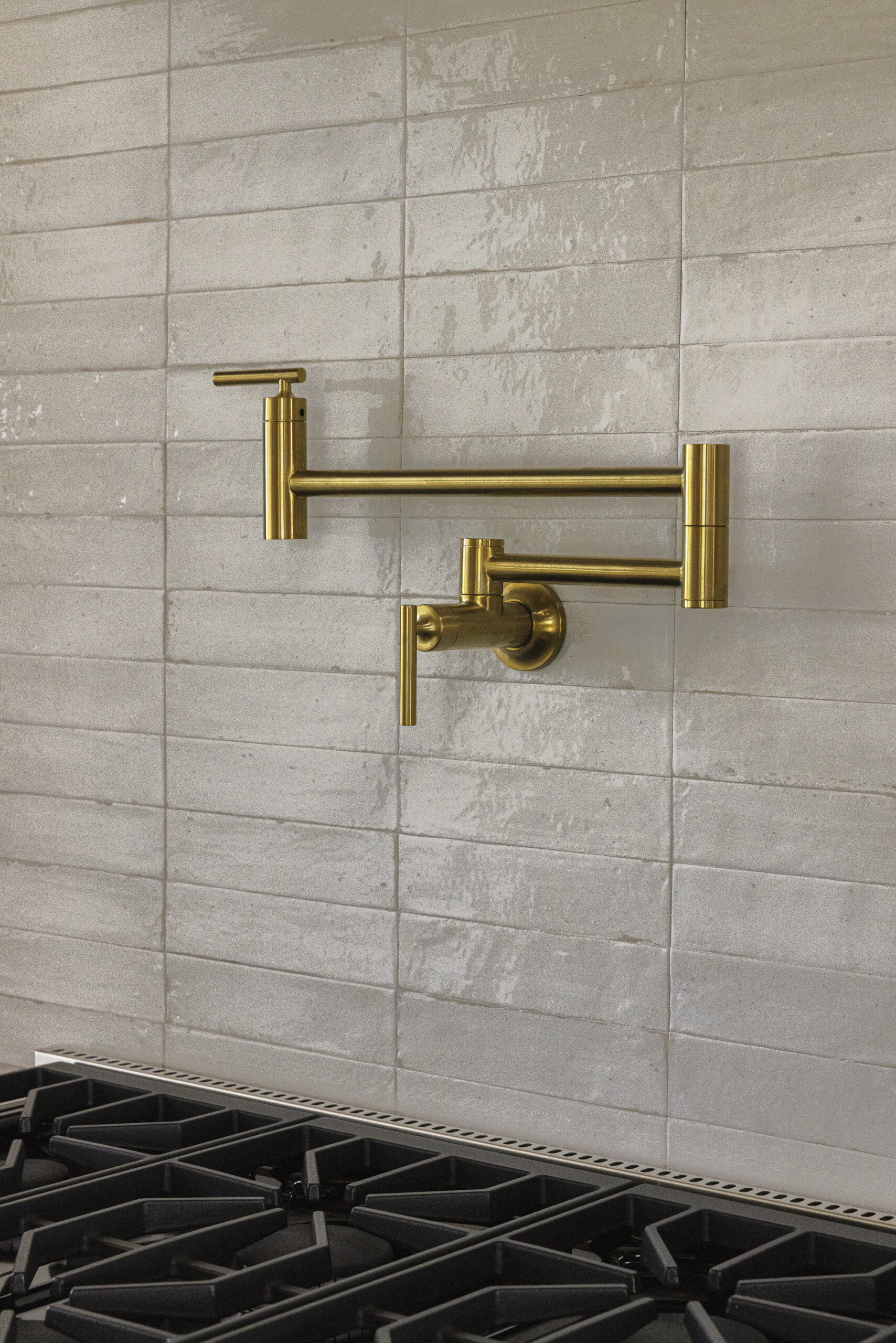 Glossy rectangular tile with brushed gold pot filler above stovetop