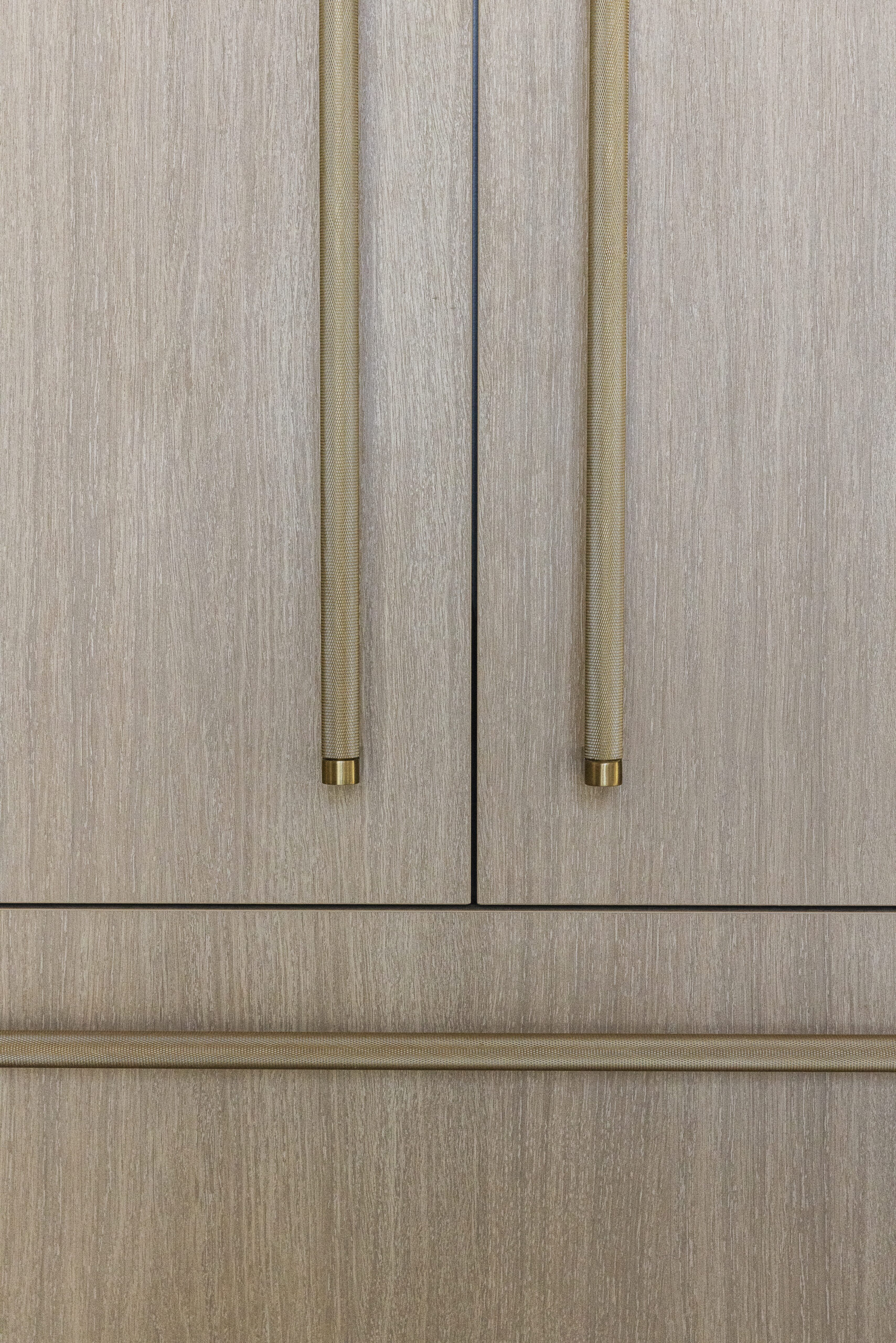 Light natural wood stained refrigerator door with oversized brushed gold door and drawer pulls