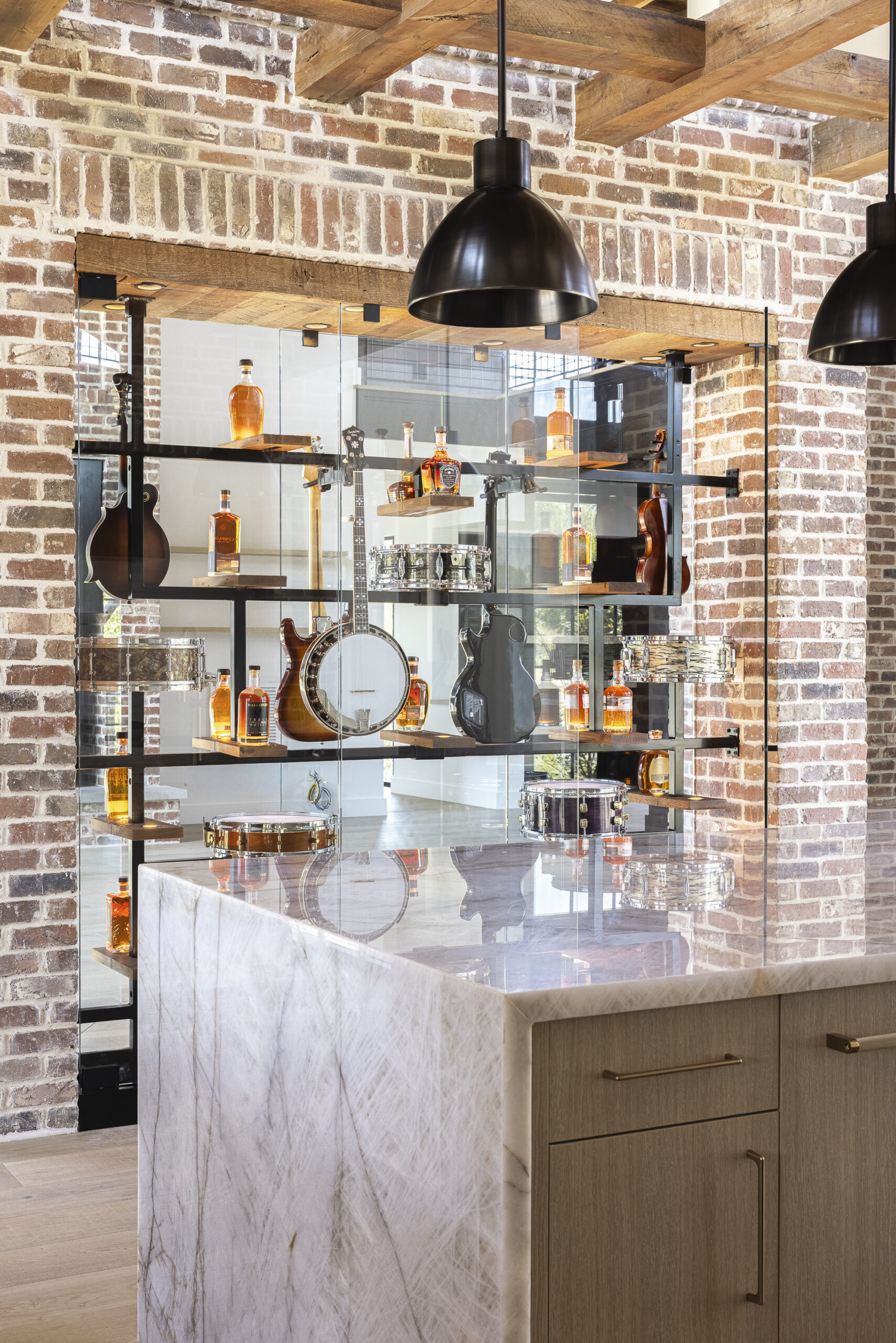 Kitchen view of a glass display case featuring a drum and guitar and bottles of bourbon