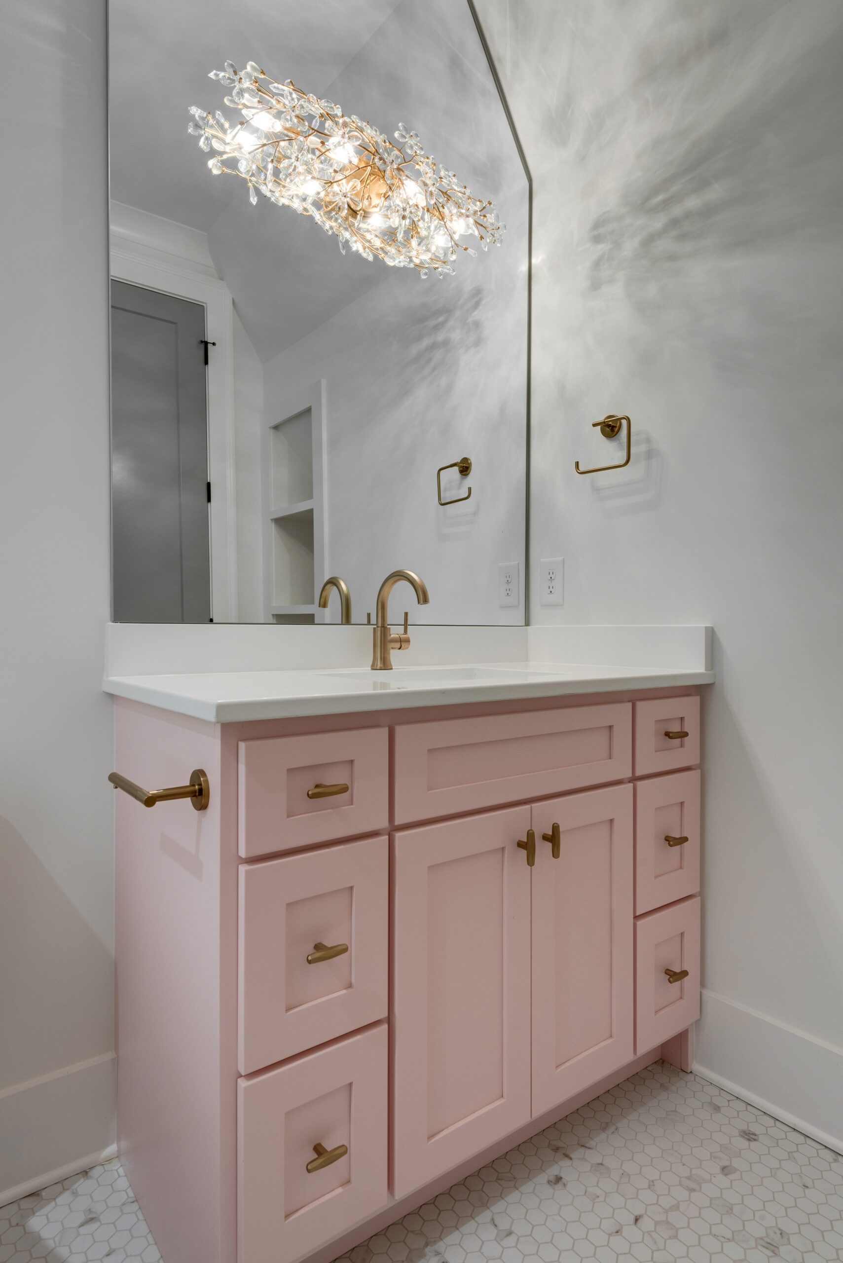 Pale pink vanity with mirror and decorative lighting above mirror