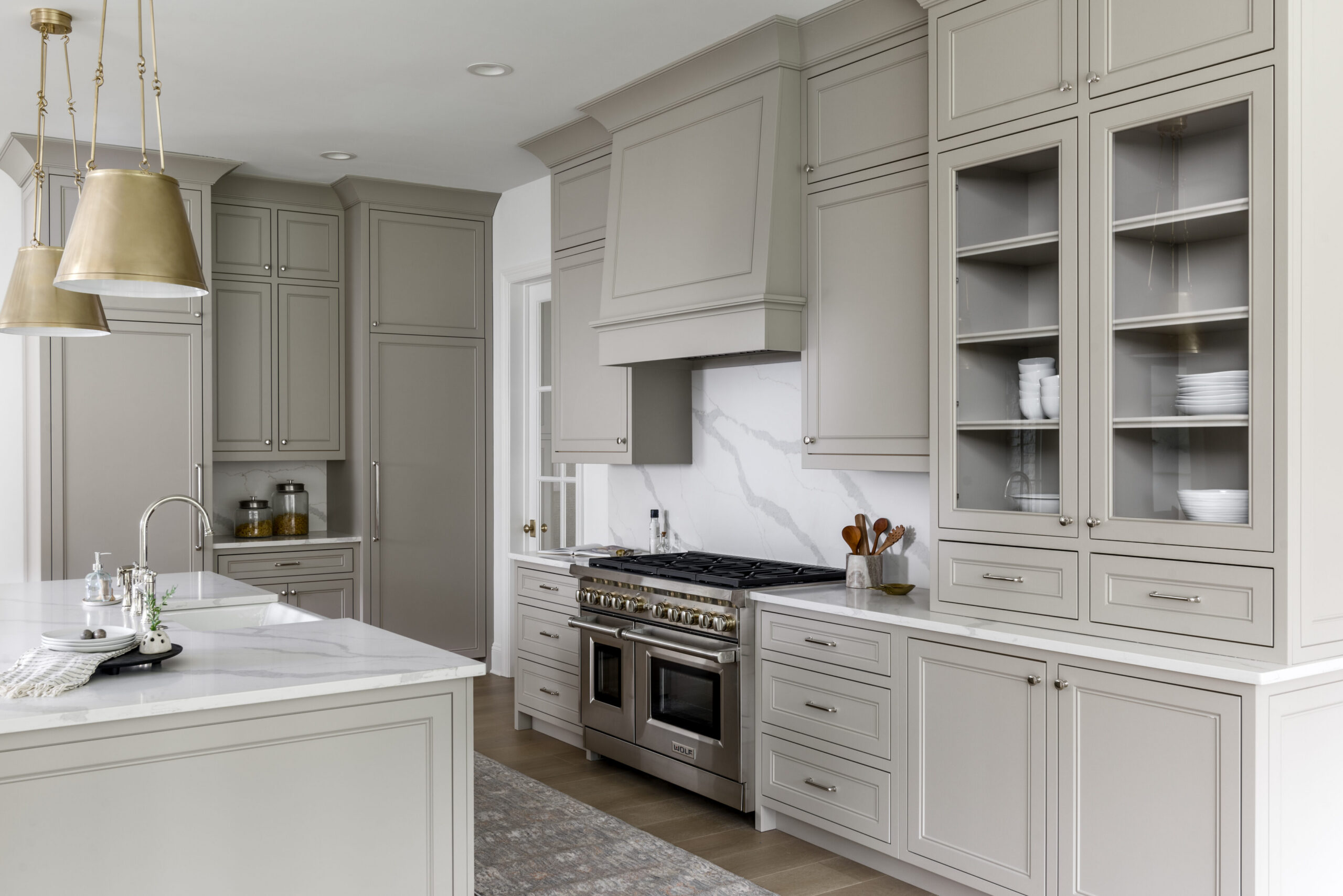 Kitchen with light gray cabinets and white countertops with range and hood