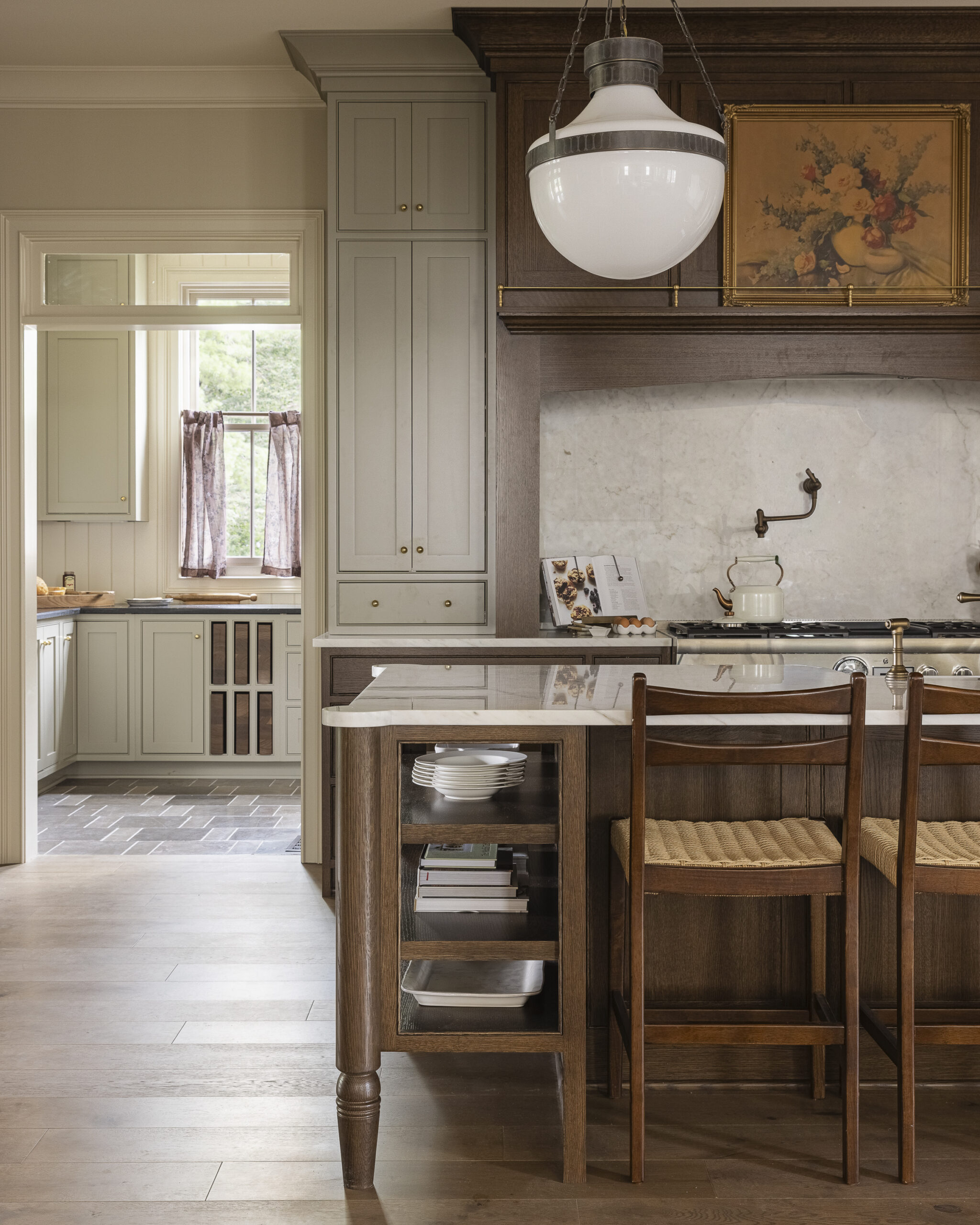 Kitchen with dark wood cabinetry, range hood, and island with white glass pendant