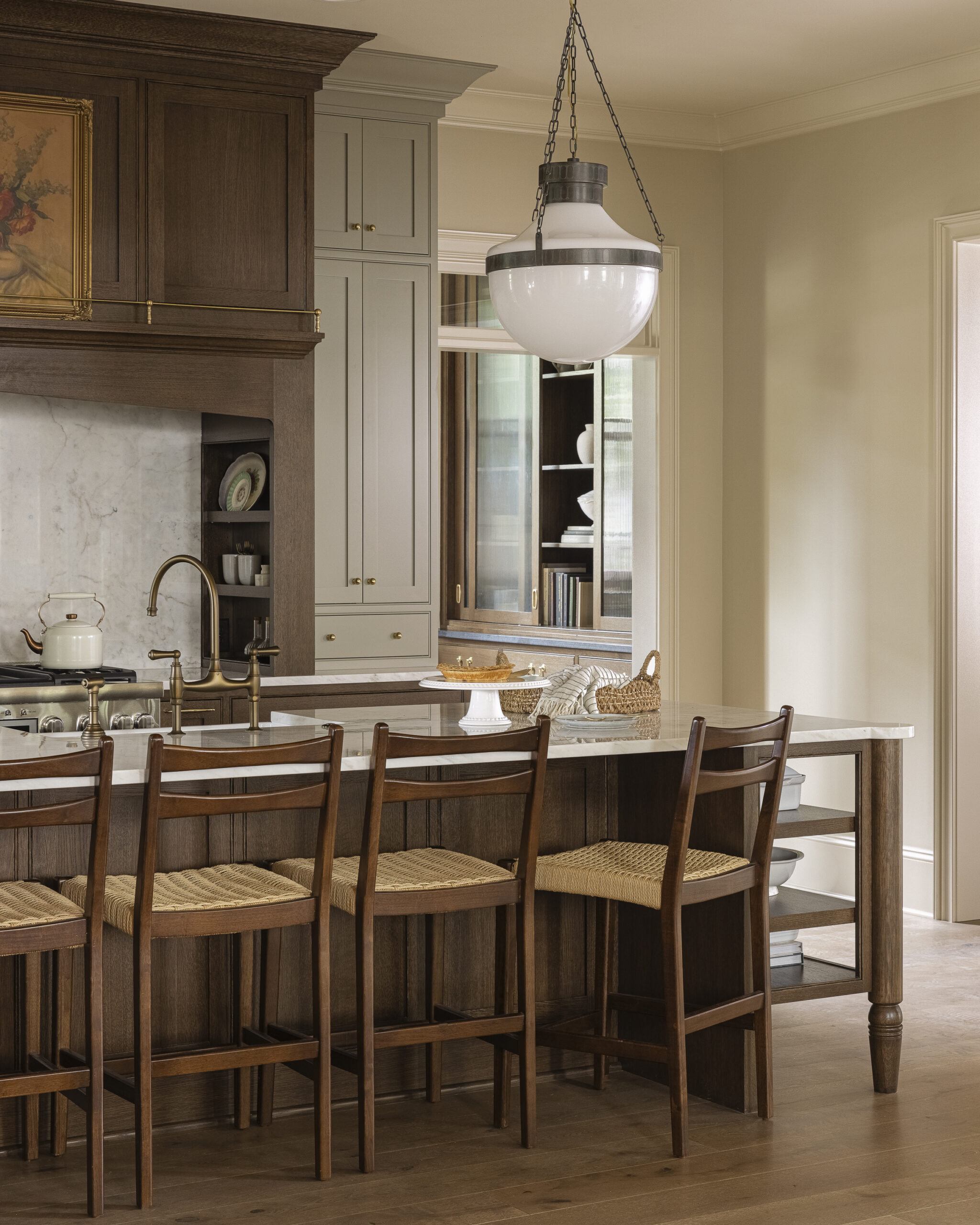 Kitchen with dark wood cabinetry, range hood, and island with white glass pendant