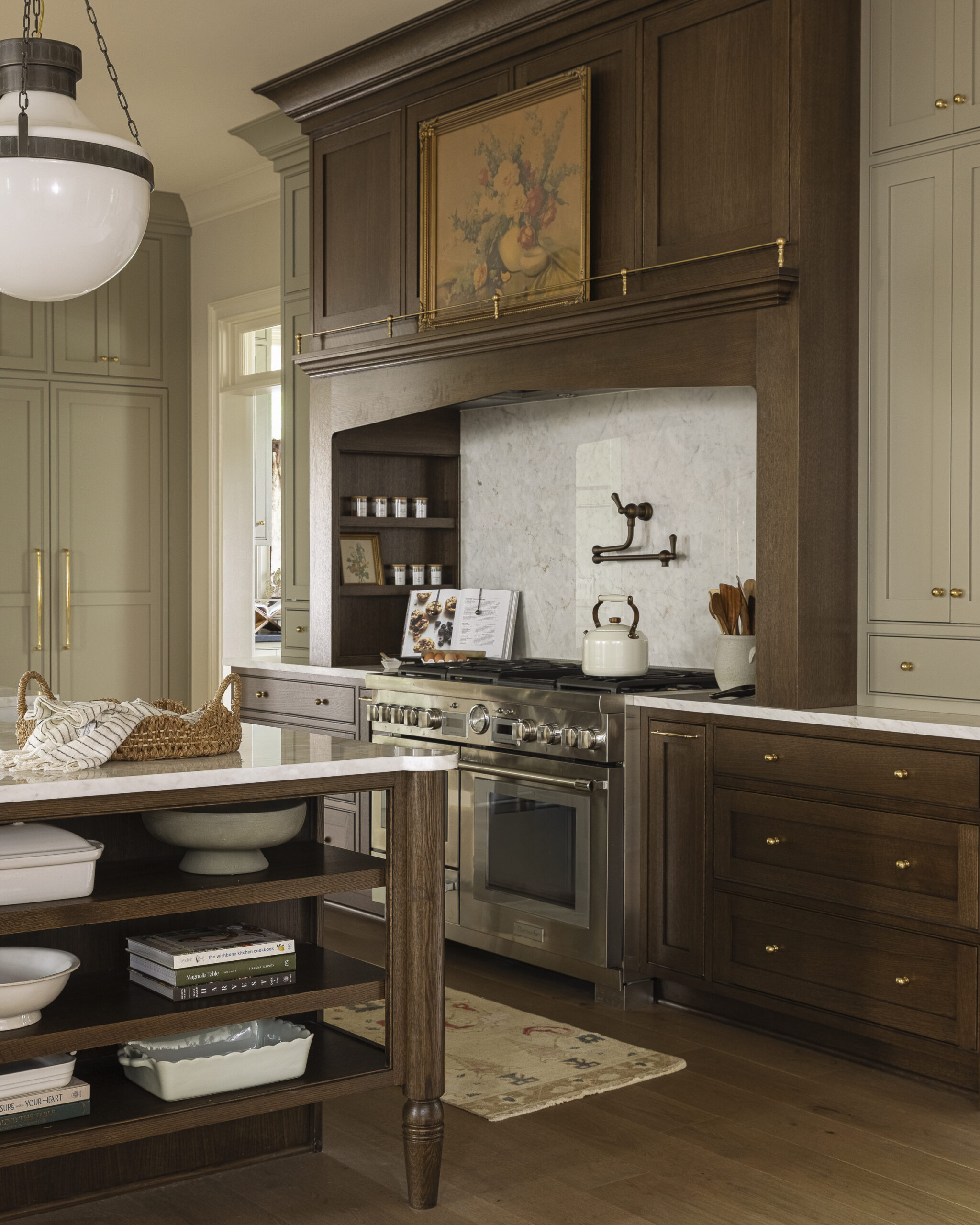 Kitchen with dark wood cabinetry, range hood, and island with white glass pendant