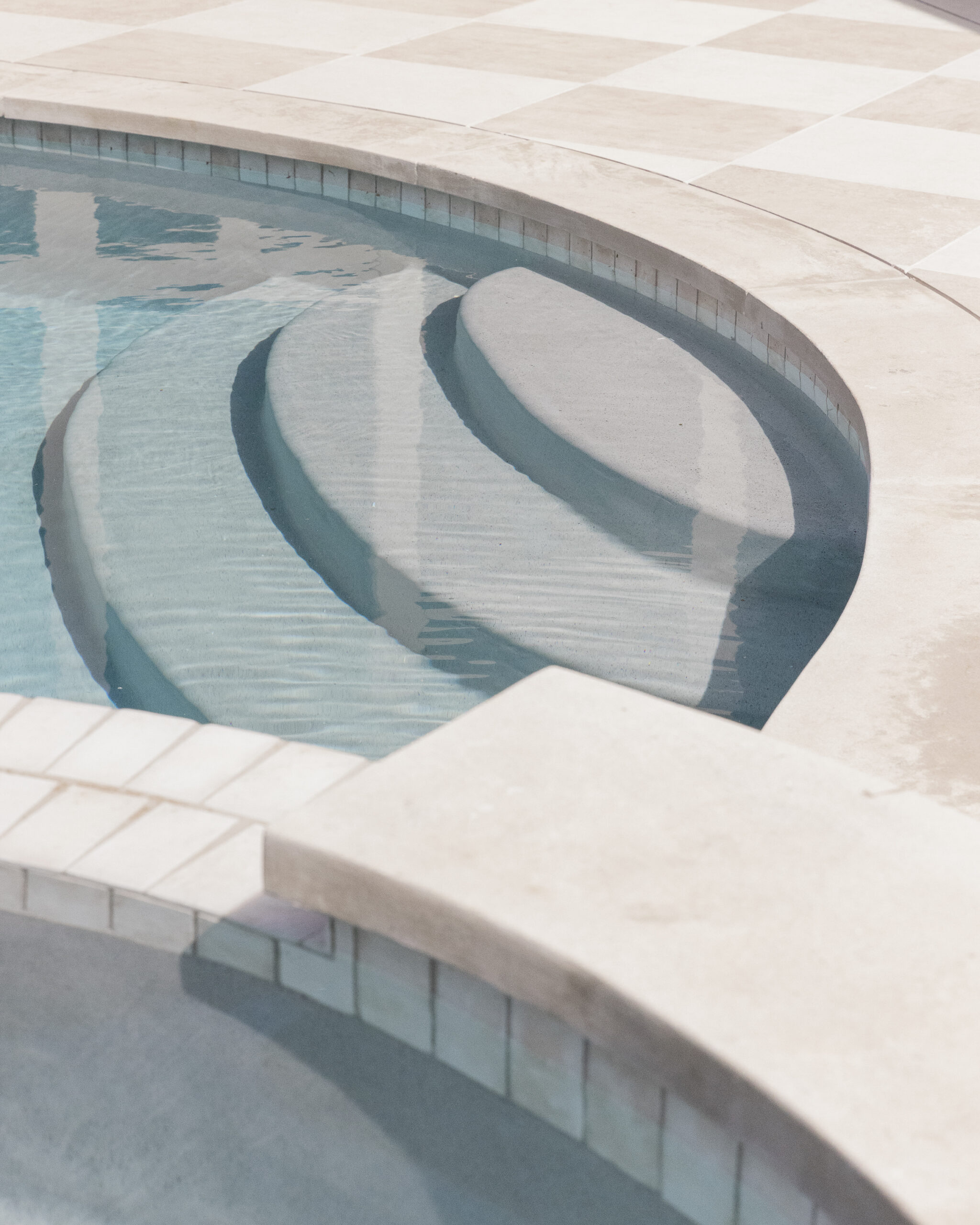 Curved pool steps with light tiled patio floor