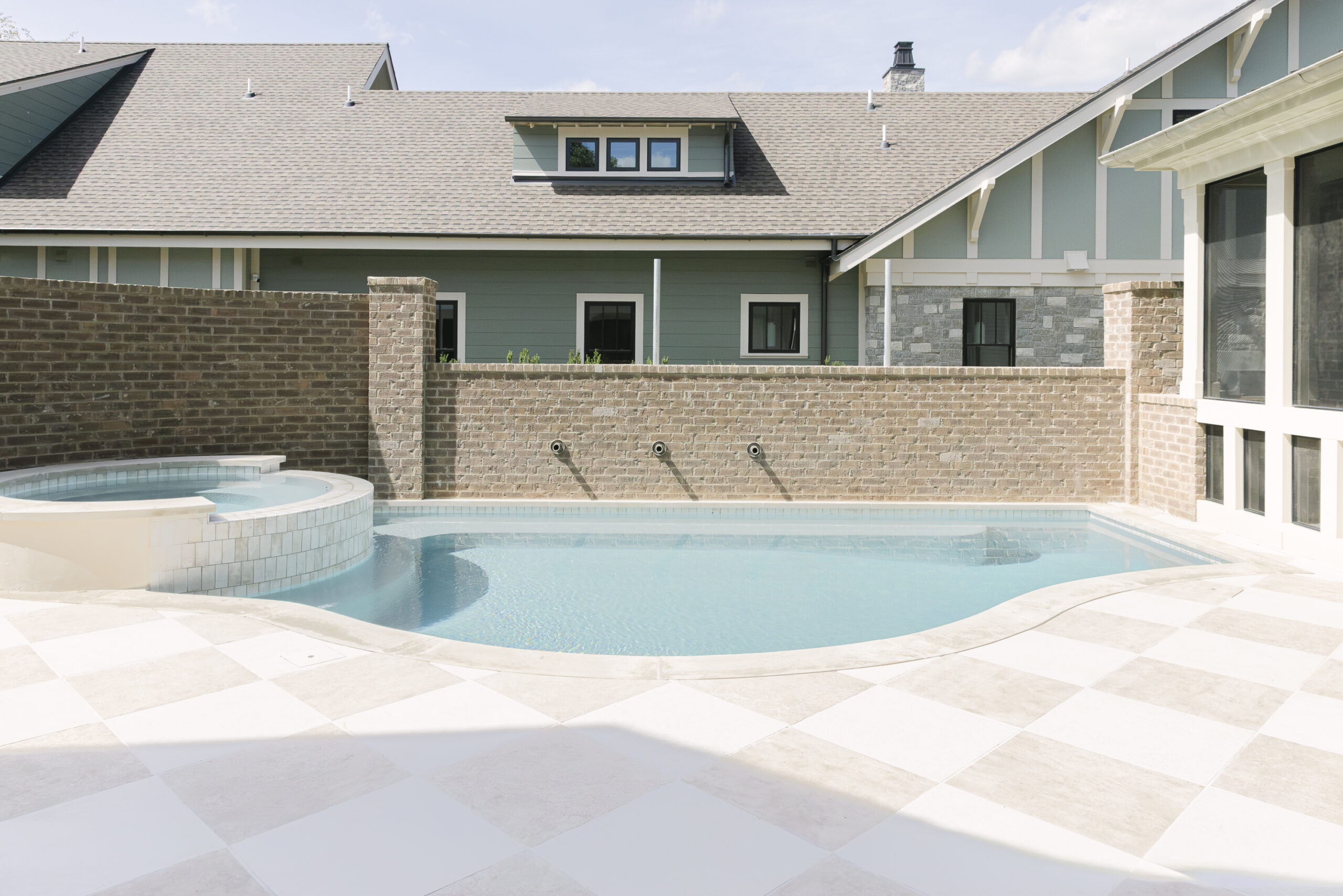 Plunge pool with brick privacy wall and tan and white diamond pattern tile floor