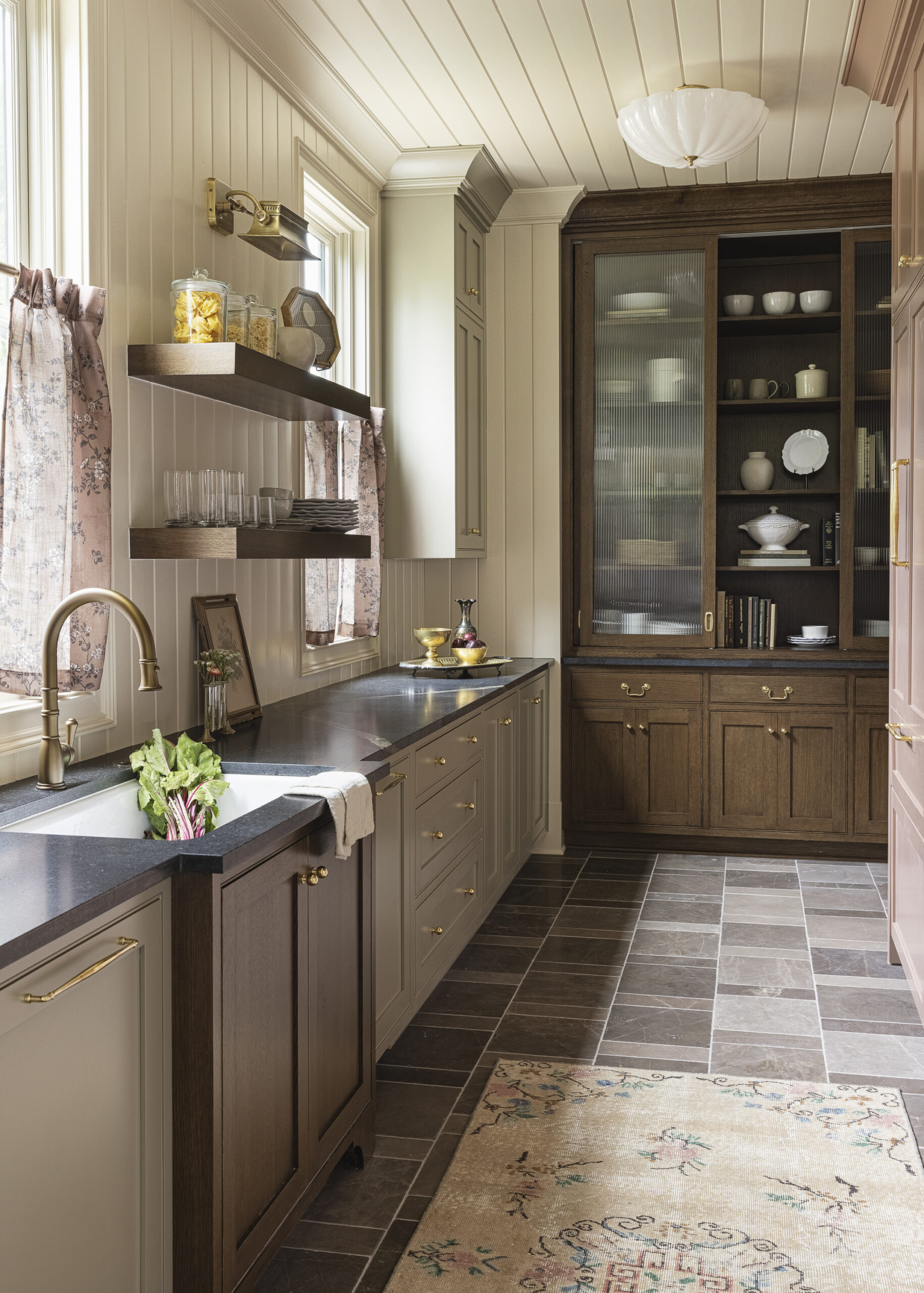 Reeded glass dark wood hutch in scullery and open shelving with cream paneled wall with windows
