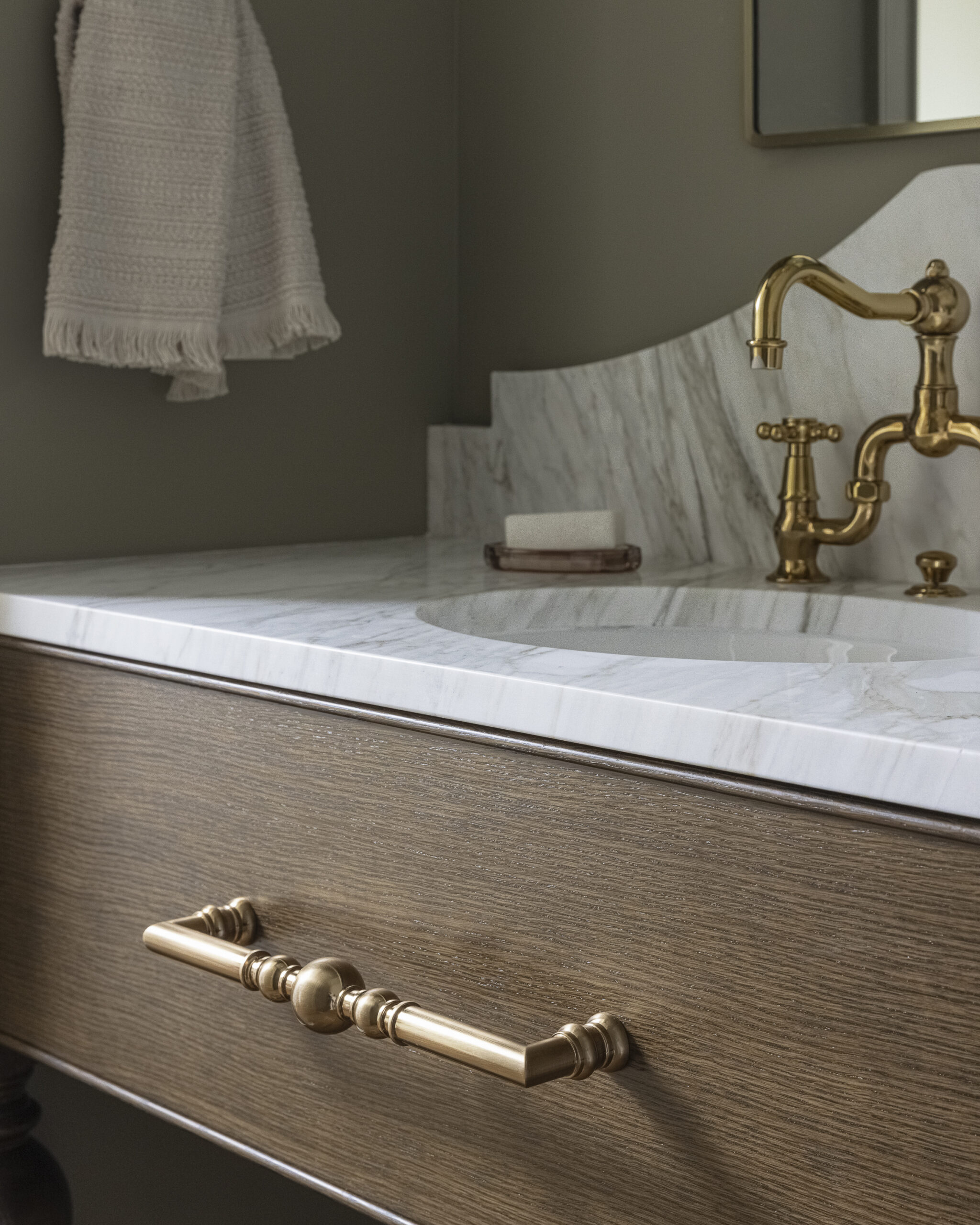 Bathroom with wood stained vanity, marble countertop with brushed gold fixtures a mirror and sconces