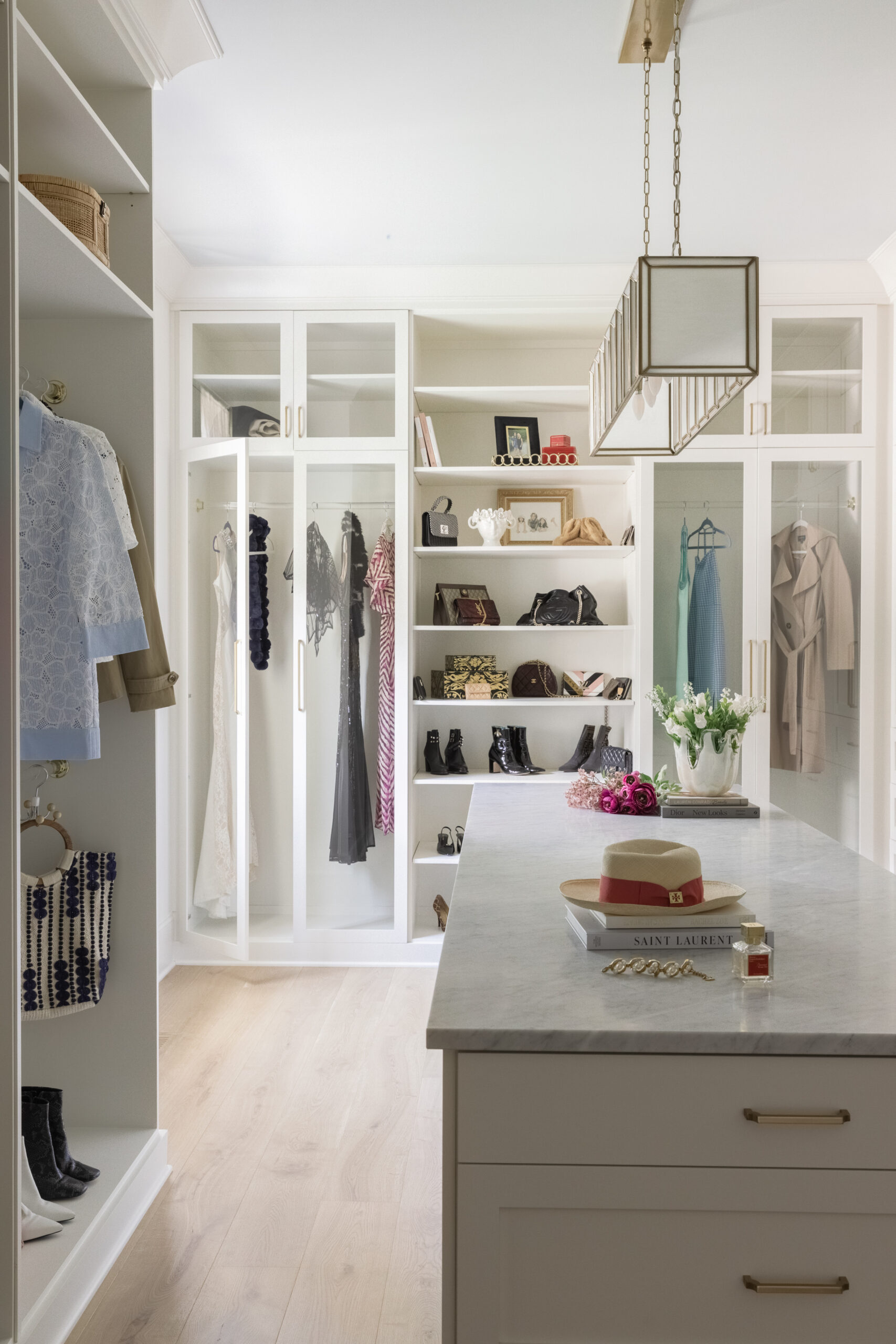 Large white walk-in closet with open shelving, and a center island with a mirror and light