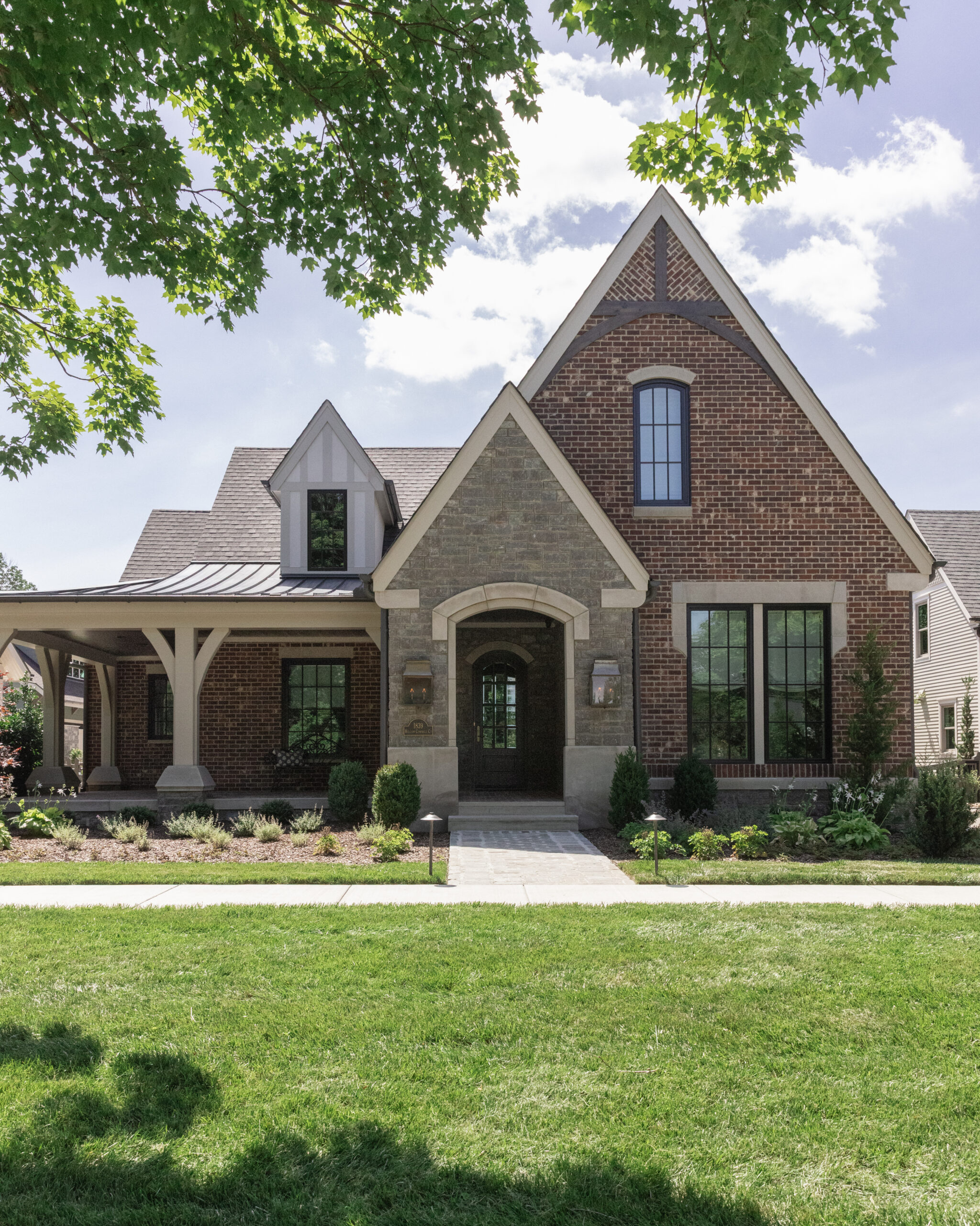 Front view of brick house with steep roof lines and a stone pathway to the front door