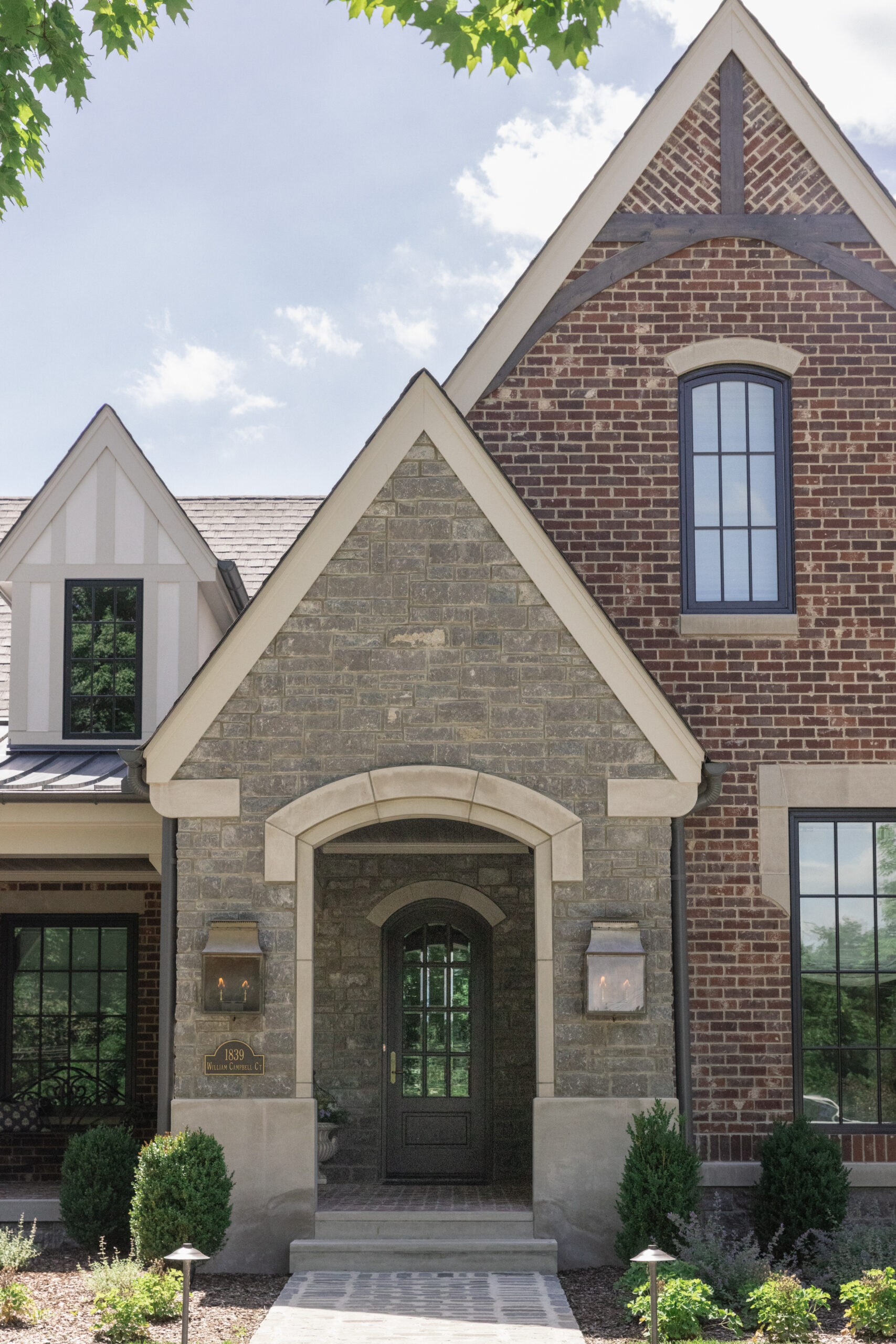 Front view of brick house with steep roof lines and a stone pathway to the front door