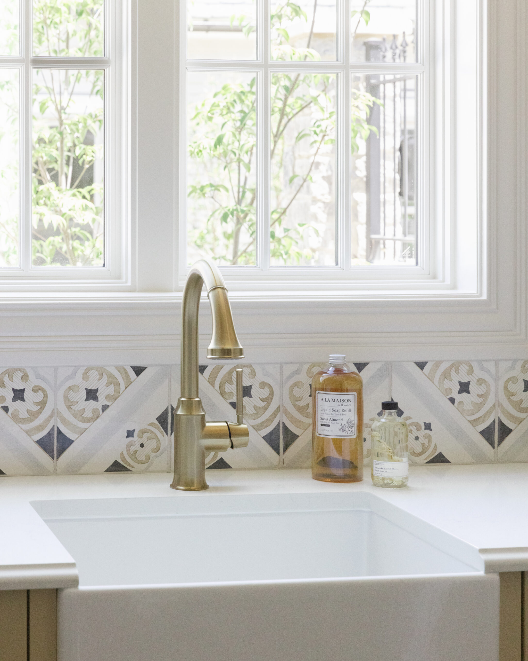 White utility sink with patterned tile backsplash and double window above
