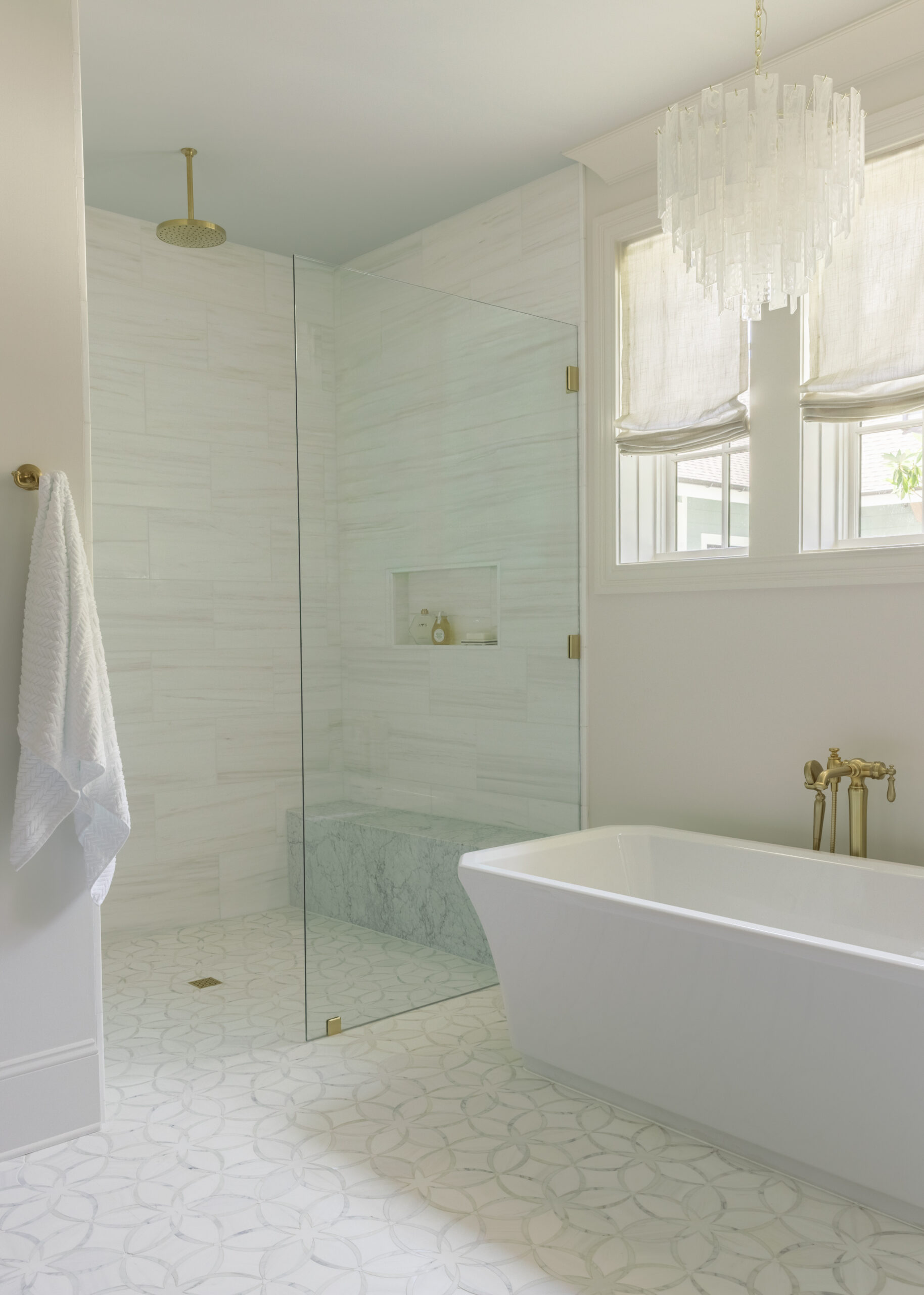 Master bath with freestanding tub under double windows and a marble glass walk-in shower
