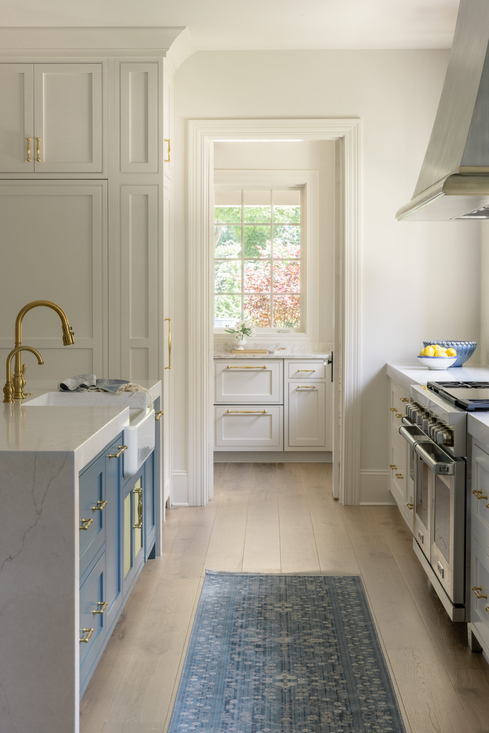 Side view of kitchen with blue kitchen island cabinets and white countertops with view of pantry