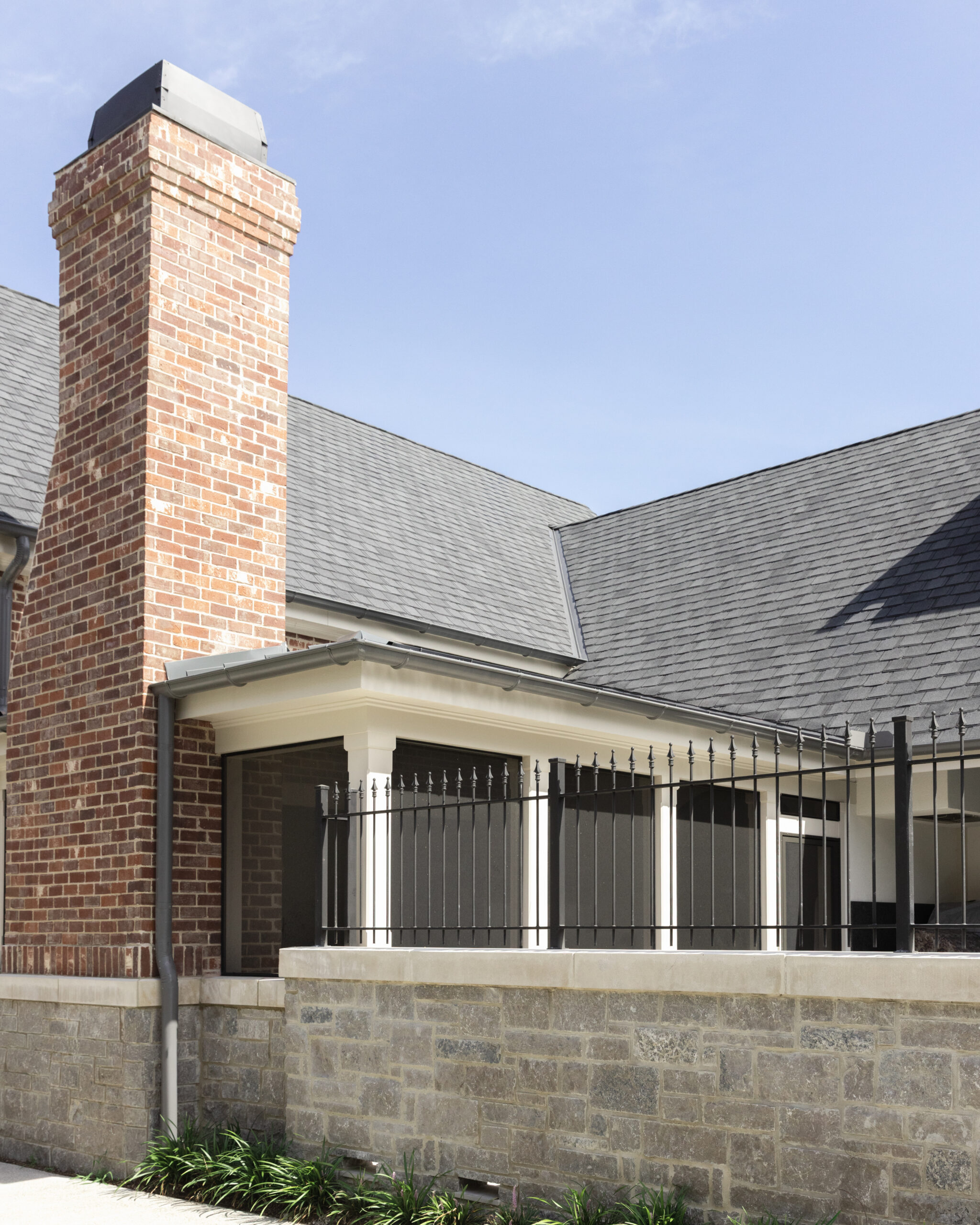 Side of brick home with screed in back patio and stone privacy wall