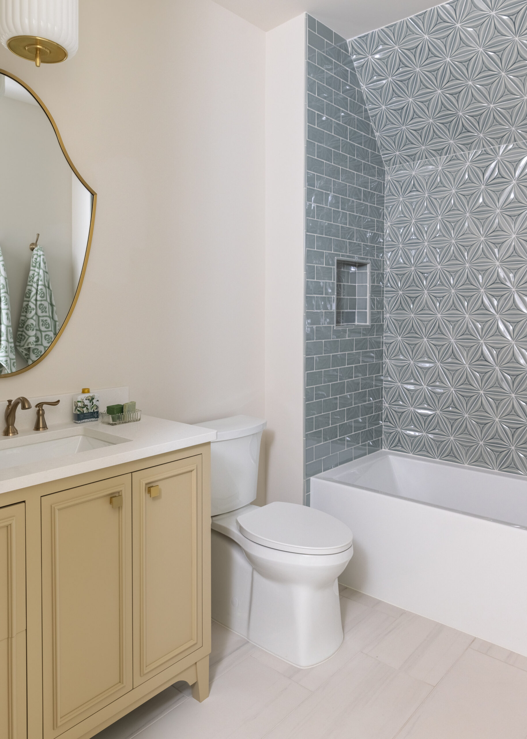 Blue subway tile with accent wall of blue tile and gold fixtures with yellow vanity