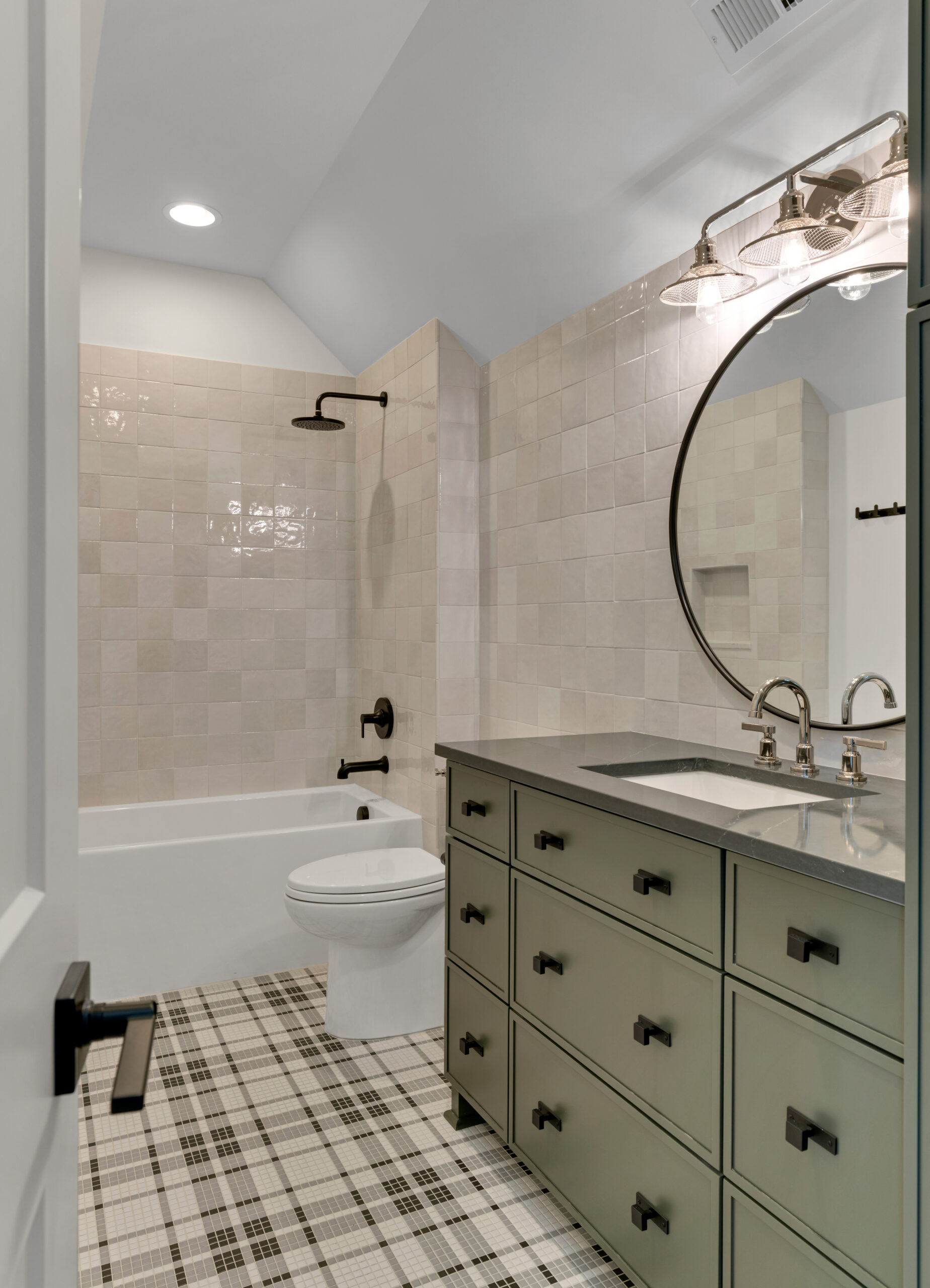 Brown and cream plaid tile floor with hunter green vanity and circular mirror