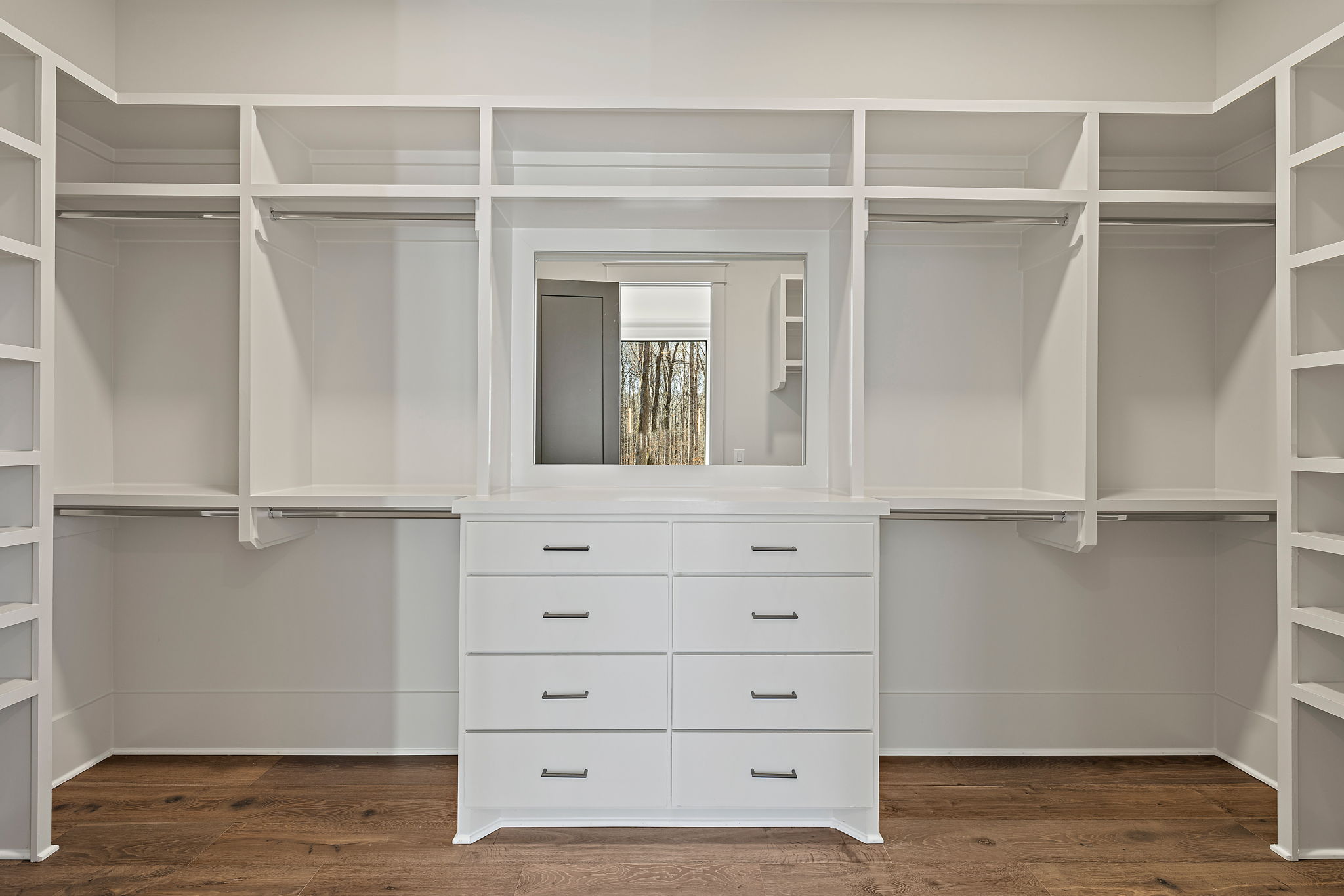 Large white walk-in closet with open shelving and a mirror and light