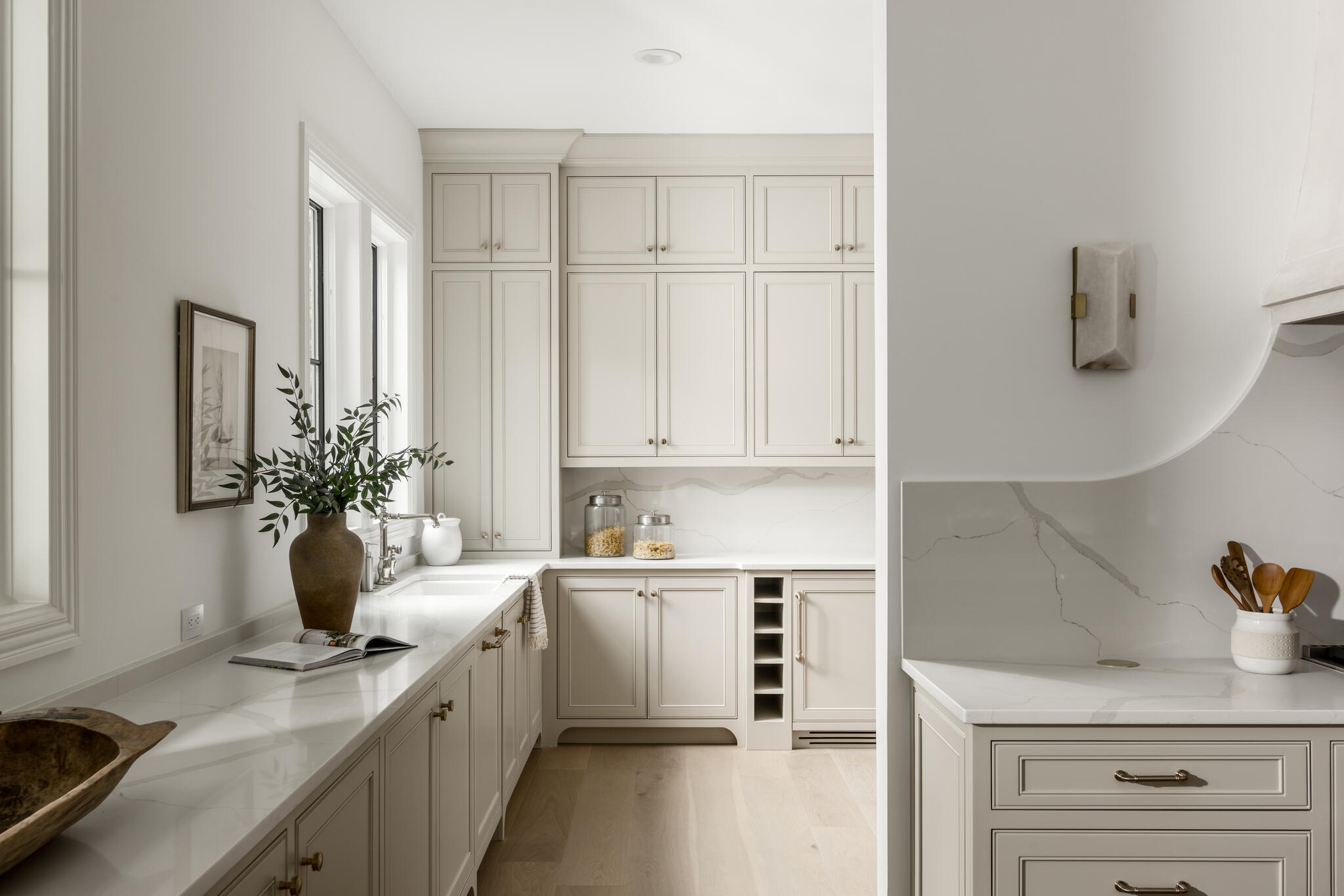 Beige cabinetry with white walls, backsplash, and countertops, windows, and beverage cooler
