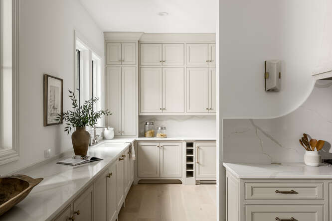 Corridor view of kitchen with light greige kitchen cabinets with light countertops