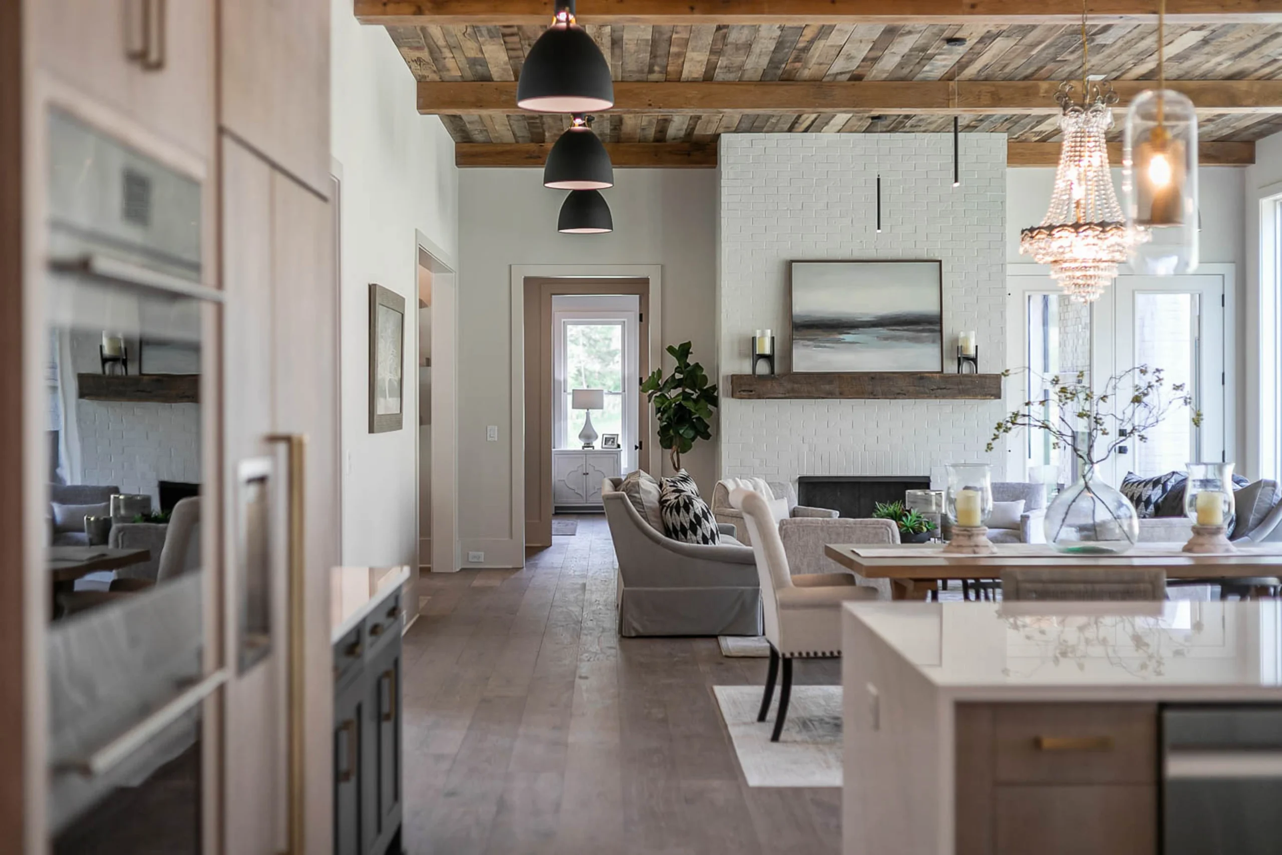Open-concept kitchen and living space with reclaimed wood ceiling, beaded chandelier, and fireplace
